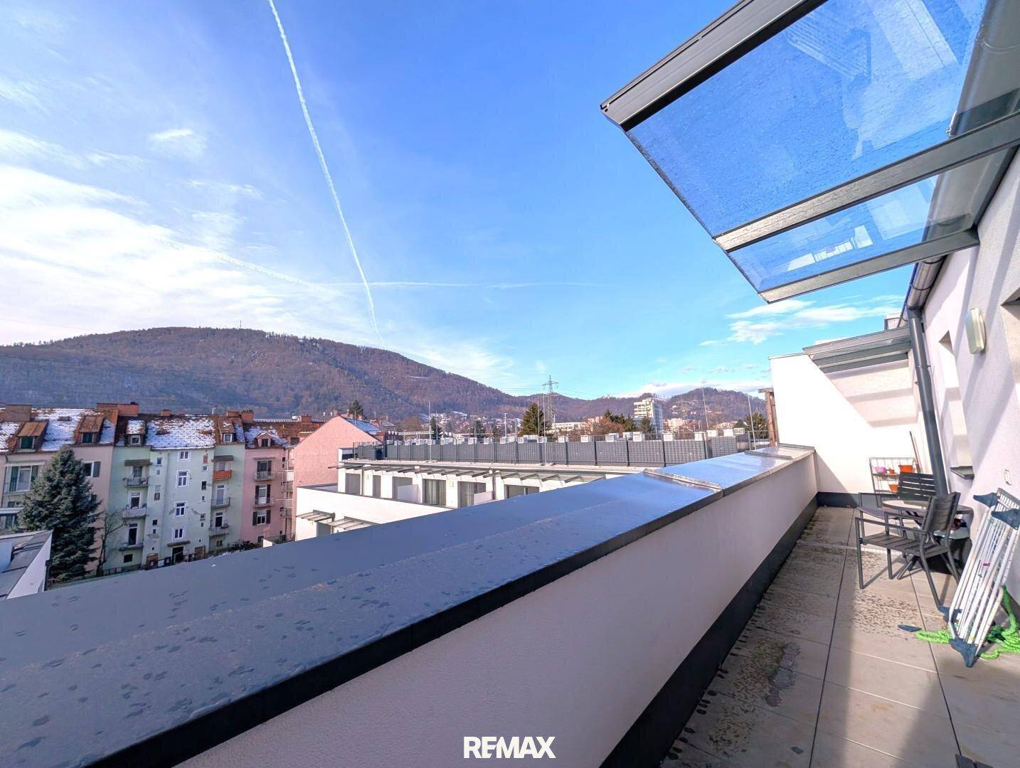 Großer Balkon mit Glasüberdachung und weitem Blick auf die umliegende Berglandschaft.