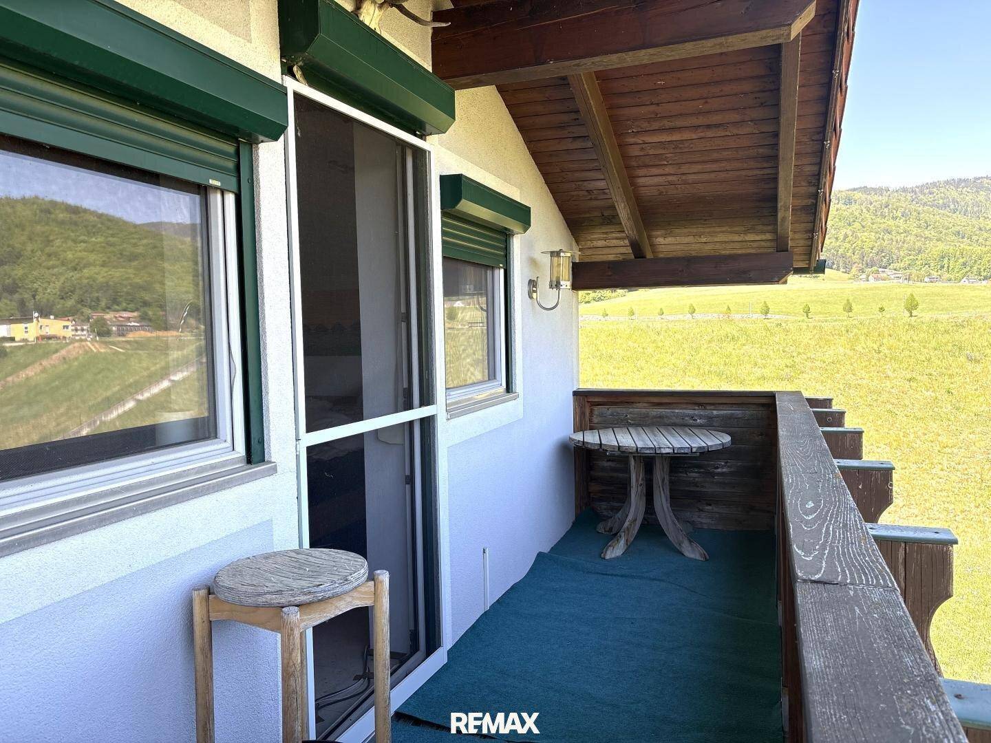 Kleiner Balkon mit Holztisch und Stuhl, bietet einen weiten Blick auf die grüne Landschaft.