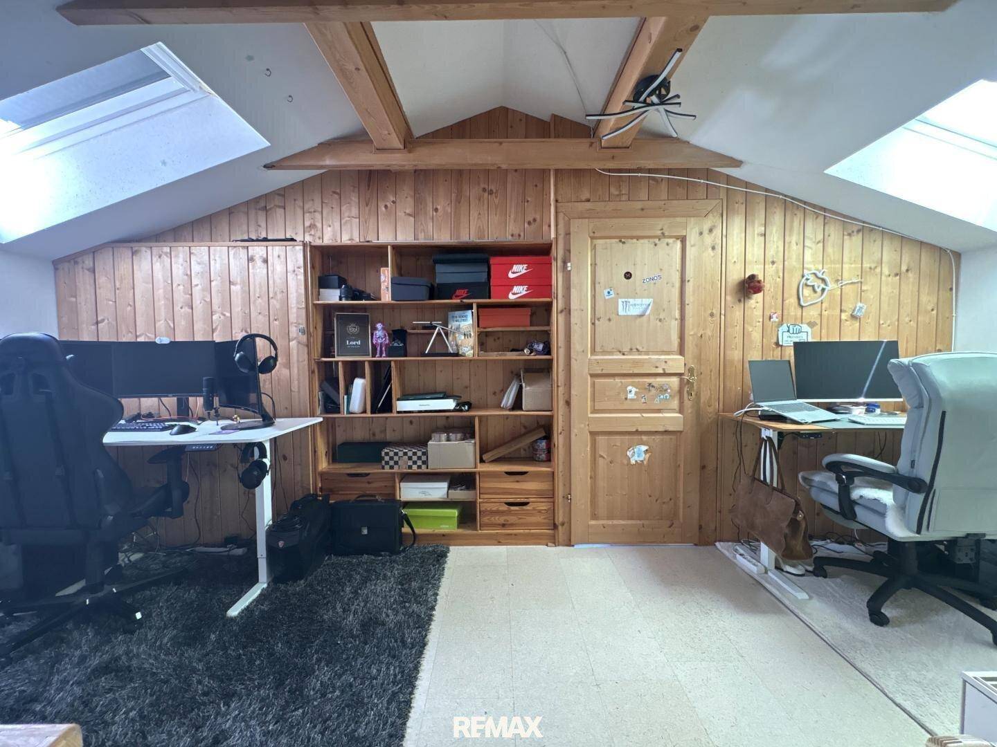 Geräumiges Büro im Dachgeschoss mit Holzvertäfelung, Schreibtischen und Dachfenstern für viel Licht.