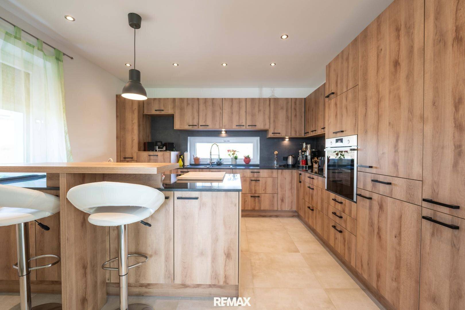 Moderne Holzküche mit integrierten Geräten, Kücheninsel und Frühstücksbar für schnelles Essen.