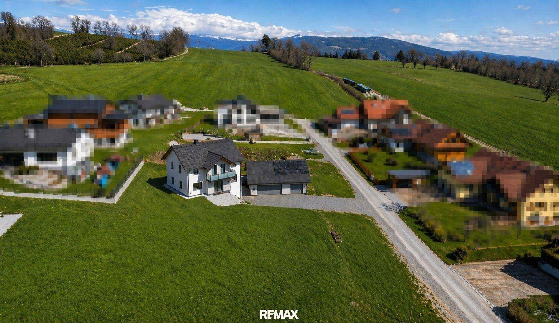 Weitläufige Luftaufnahme des Hauses mit umliegenden Feldern und Bergen im Hintergrund.