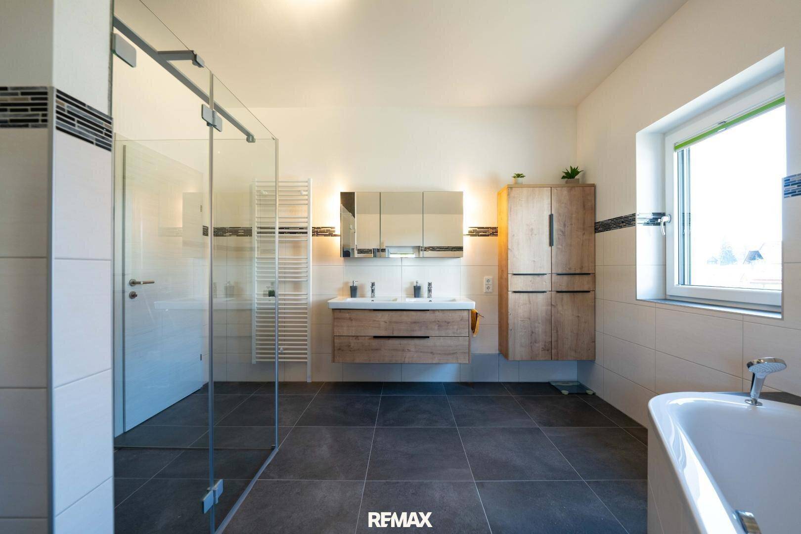 Geräumiges Badezimmer mit begehbarer Dusche, Badewanne und modernen Holzmöbeln.