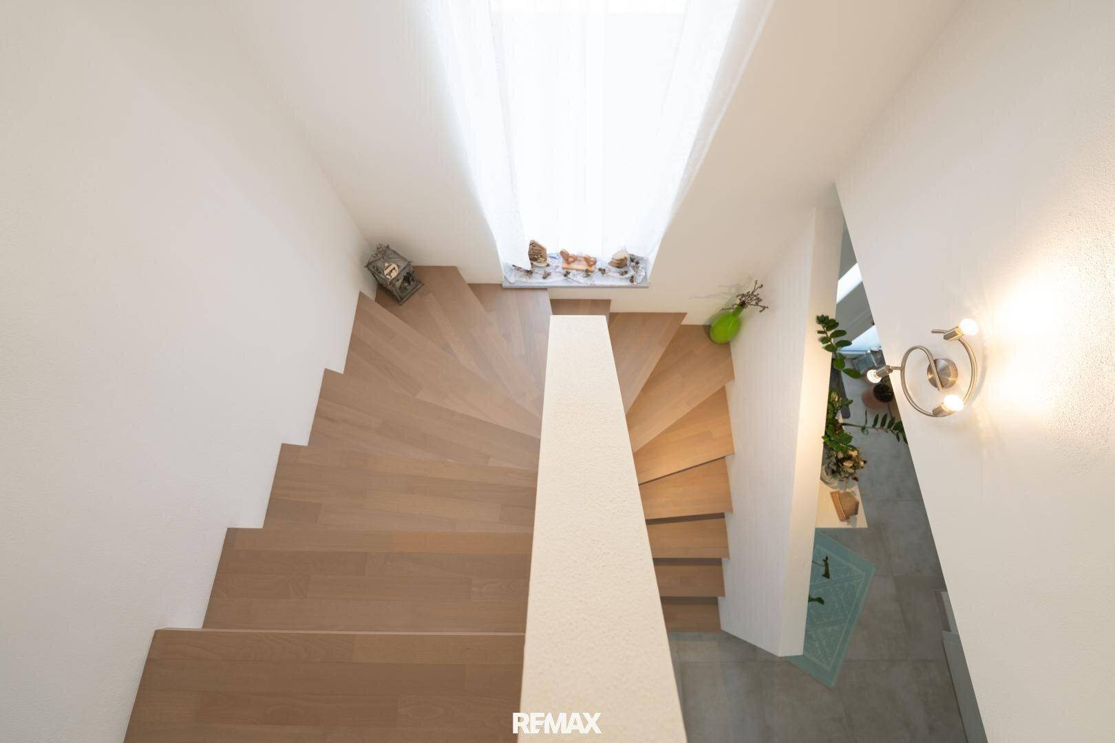 Elegante Holztreppe von oben gesehen, die die verschiedenen Ebenen des Hauses verbindet.