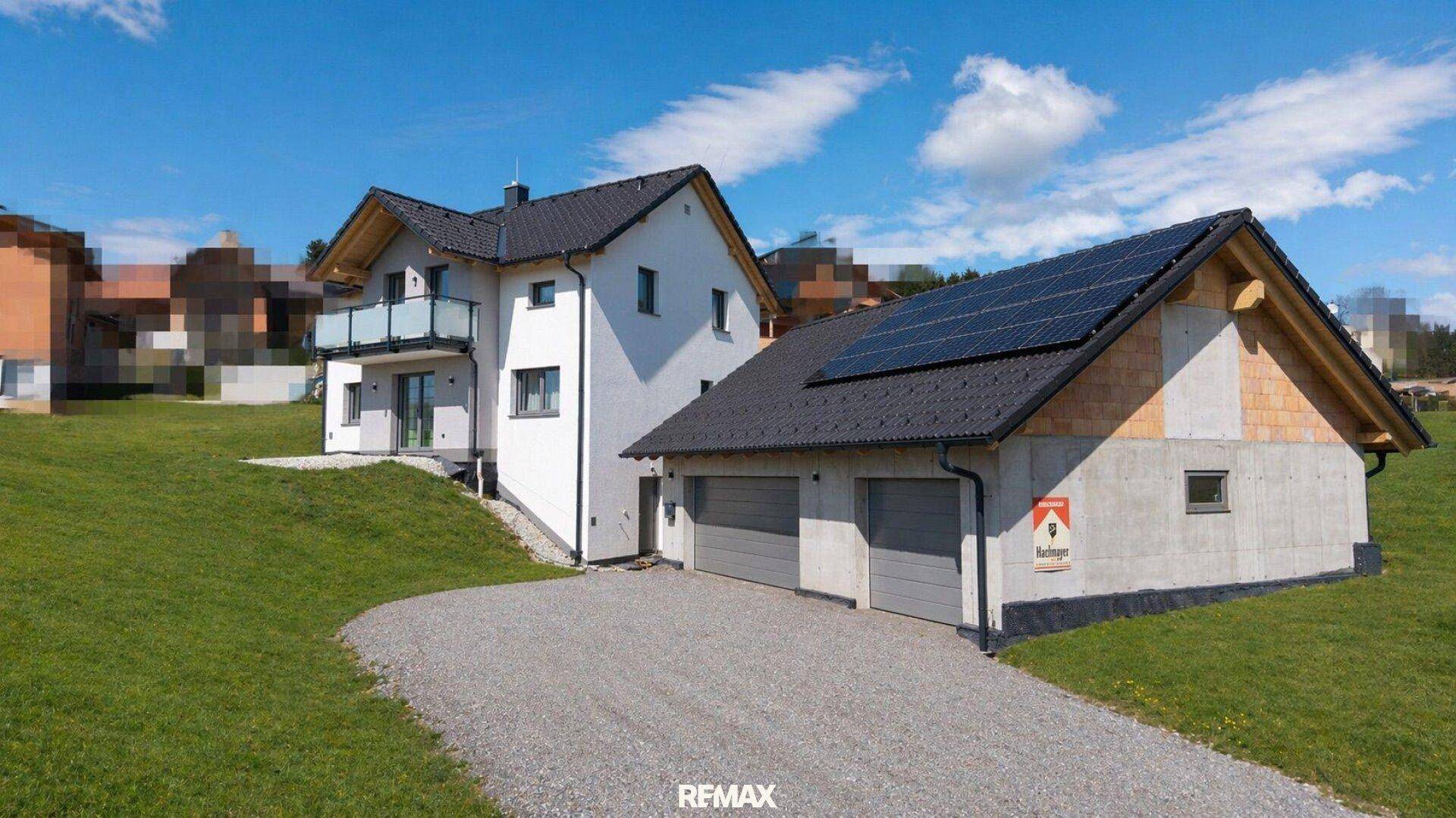 Seitenansicht des modernen Einfamilienhauses mit Doppelgarage und Photovoltaikmodulen auf dem Dach.