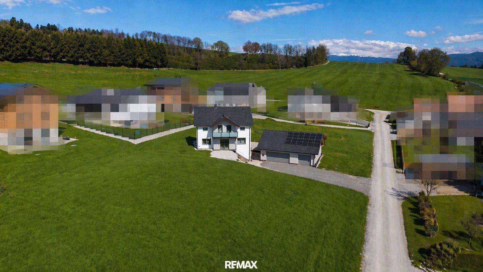 Luftaufnahme des Einfamilienhauses mit Doppelgarage und Photovoltaikanlage in ländlicher Umgebung.
