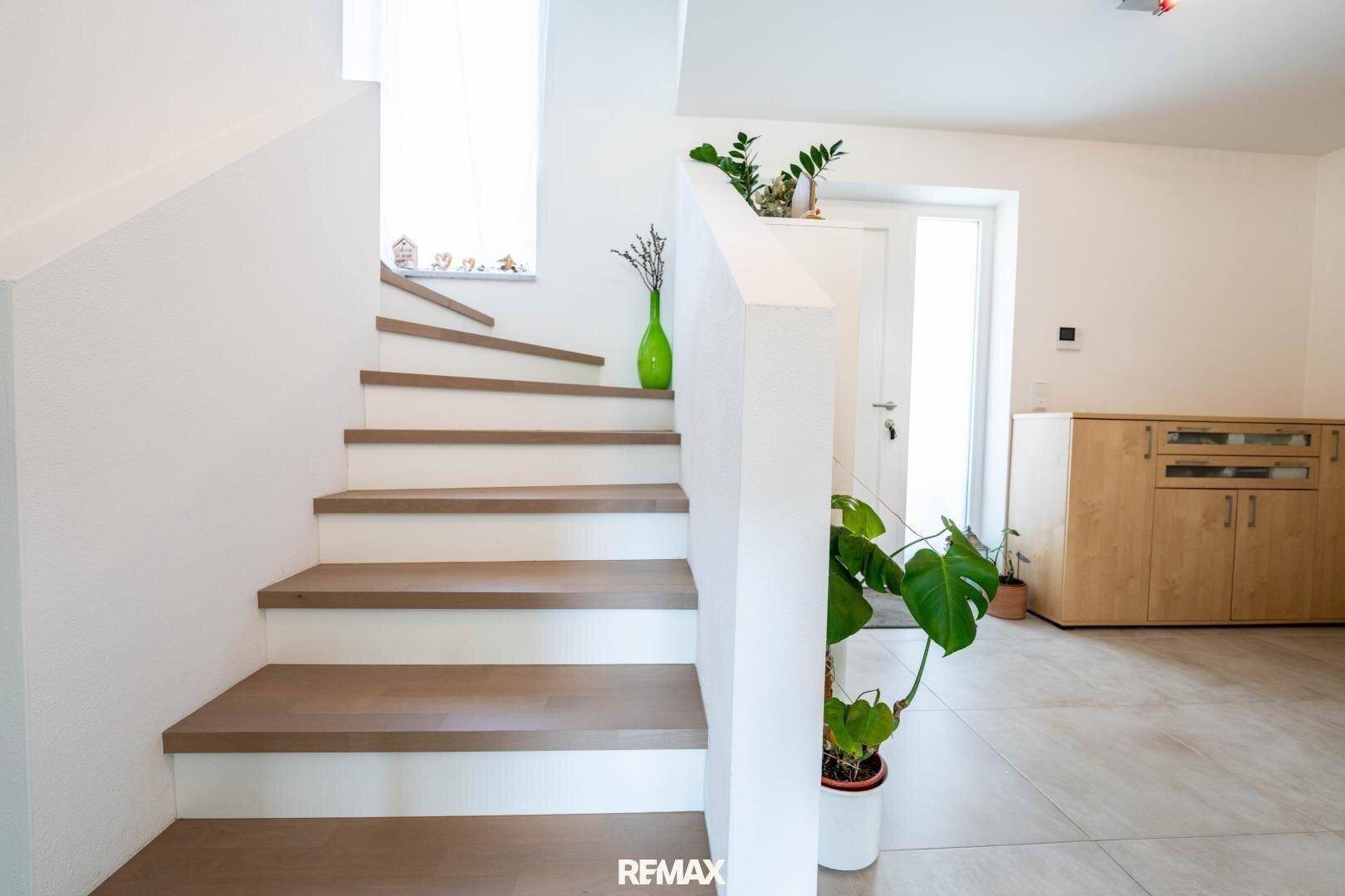 Moderne Holztreppe mit weißem Geländer, die die Etagen des Hauses elegant verbindet.