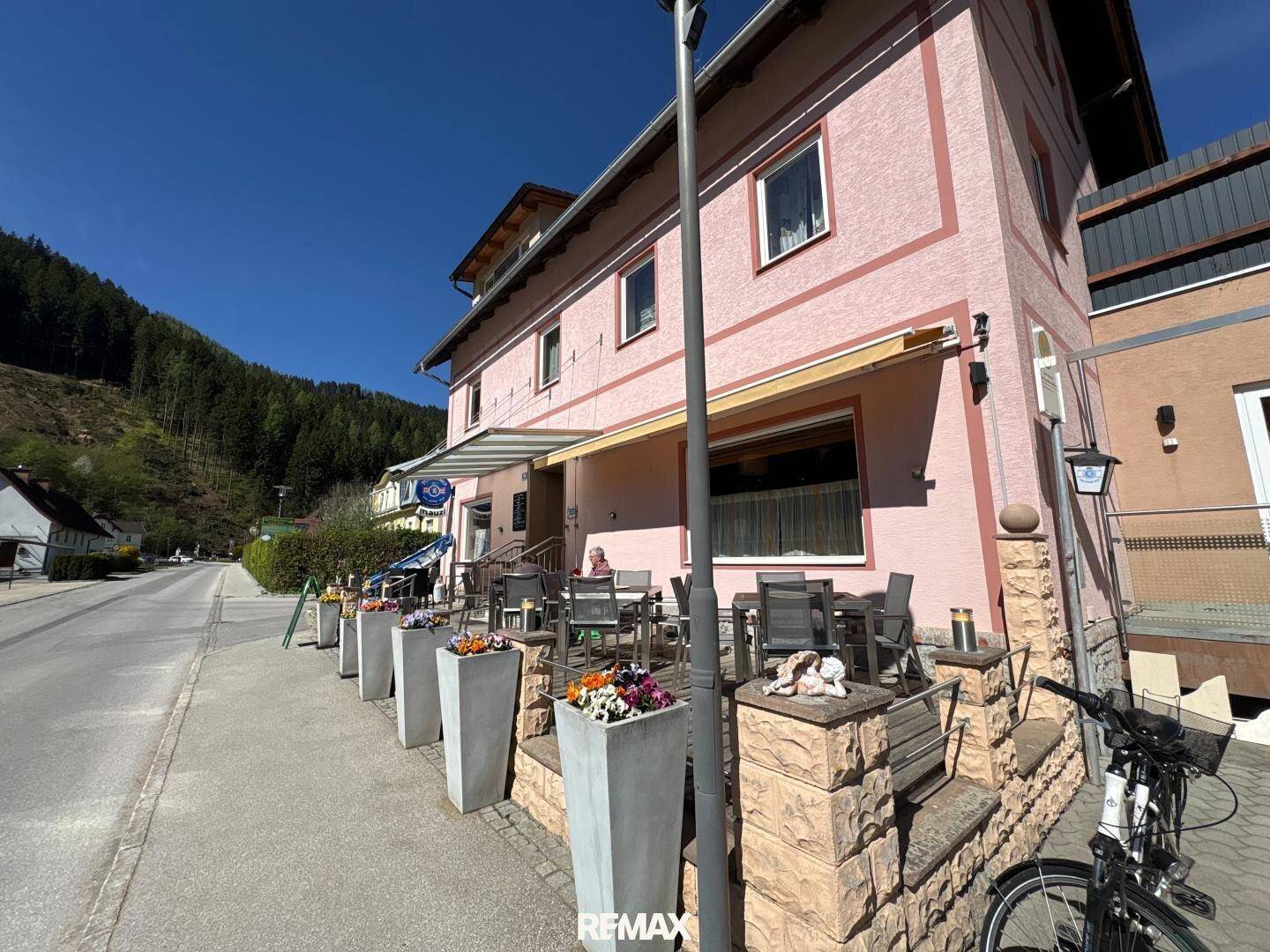Seitliche Ansicht des Gebäudes mit einer einladenden Terrasse und Blumenkübeln.