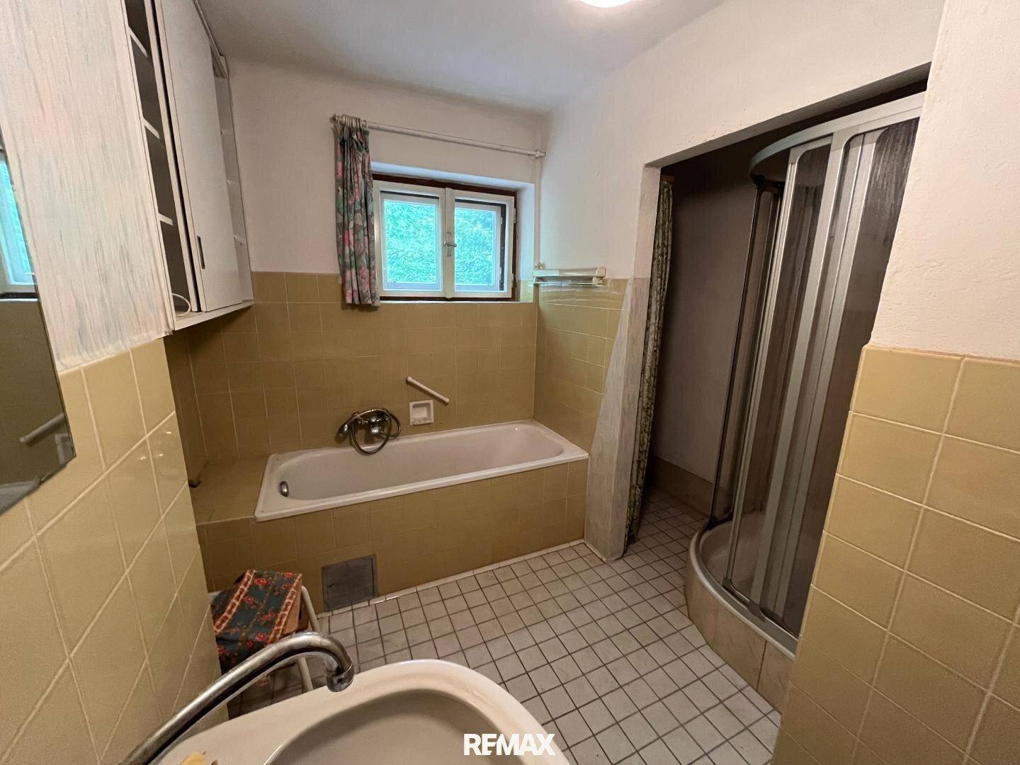 Badezimmer mit Badewanne, Duschkabine und gelben Fliesen im Retro-Stil.
