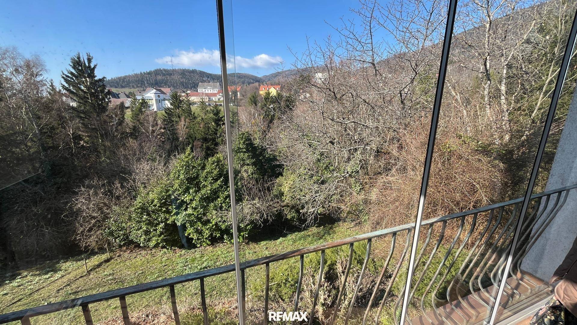 Balkon mit Glasbrüstung und weitem Blick auf die grüne Umgebung.