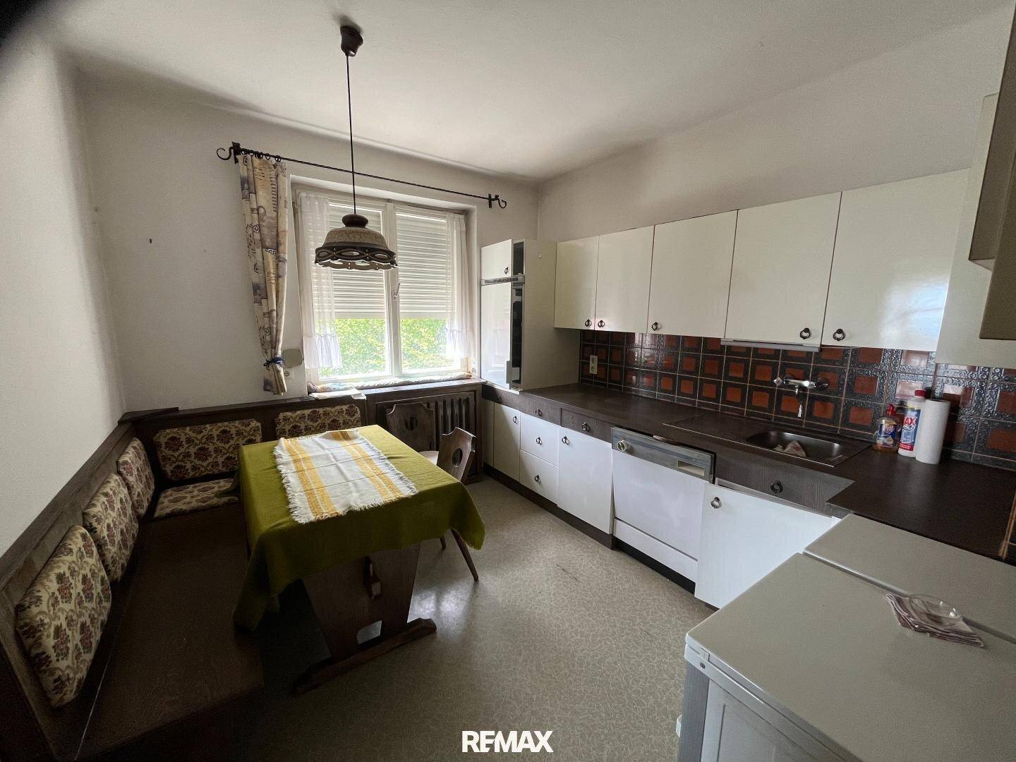 Traditionelle Küche mit Essbereich, Einbauschränken und Fenster mit Blick ins Grüne.