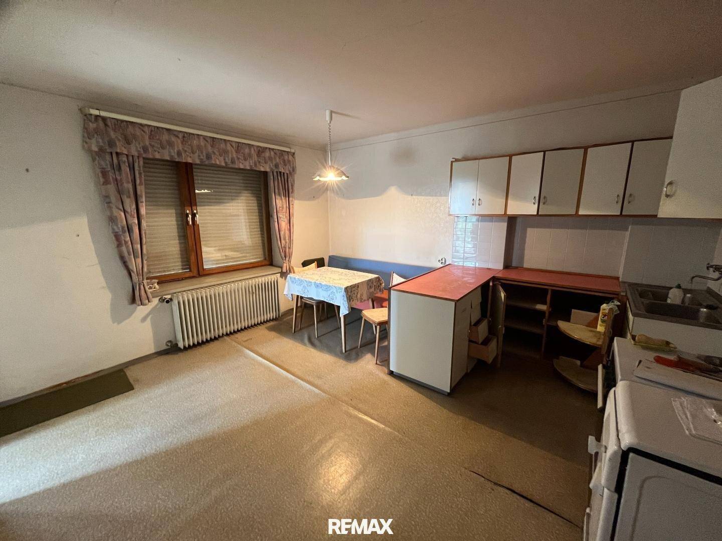 Einfache Küche mit Essbereich, Einbauschränken und Fenster.