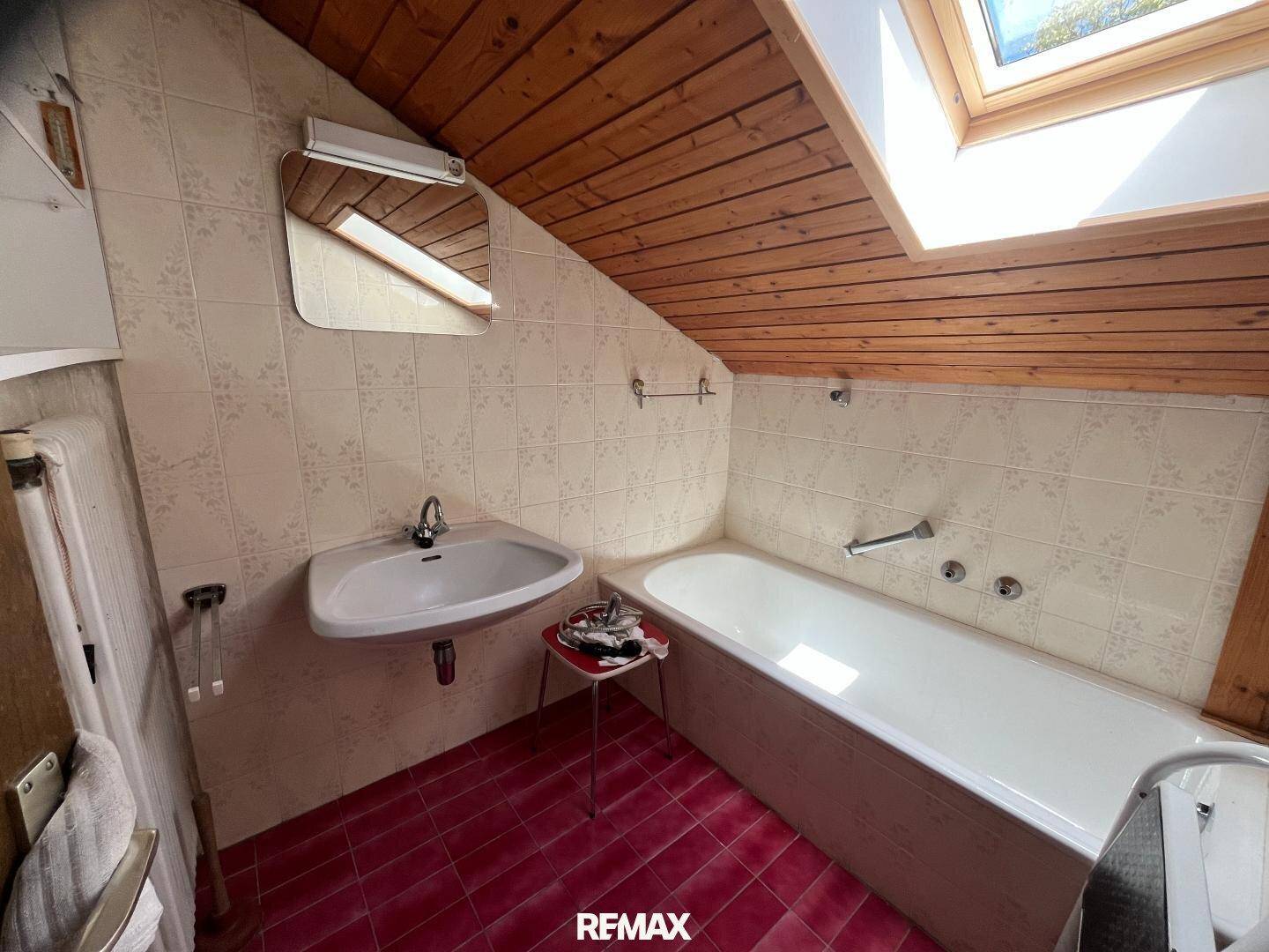 Badezimmer im Dachgeschoss mit Badewanne, Waschbecken und Dachfenster.