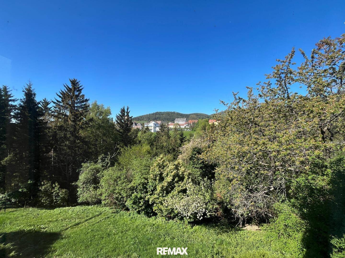 Panoramablick auf die grüne Hügellandschaft mit Häusern in der Ferne.