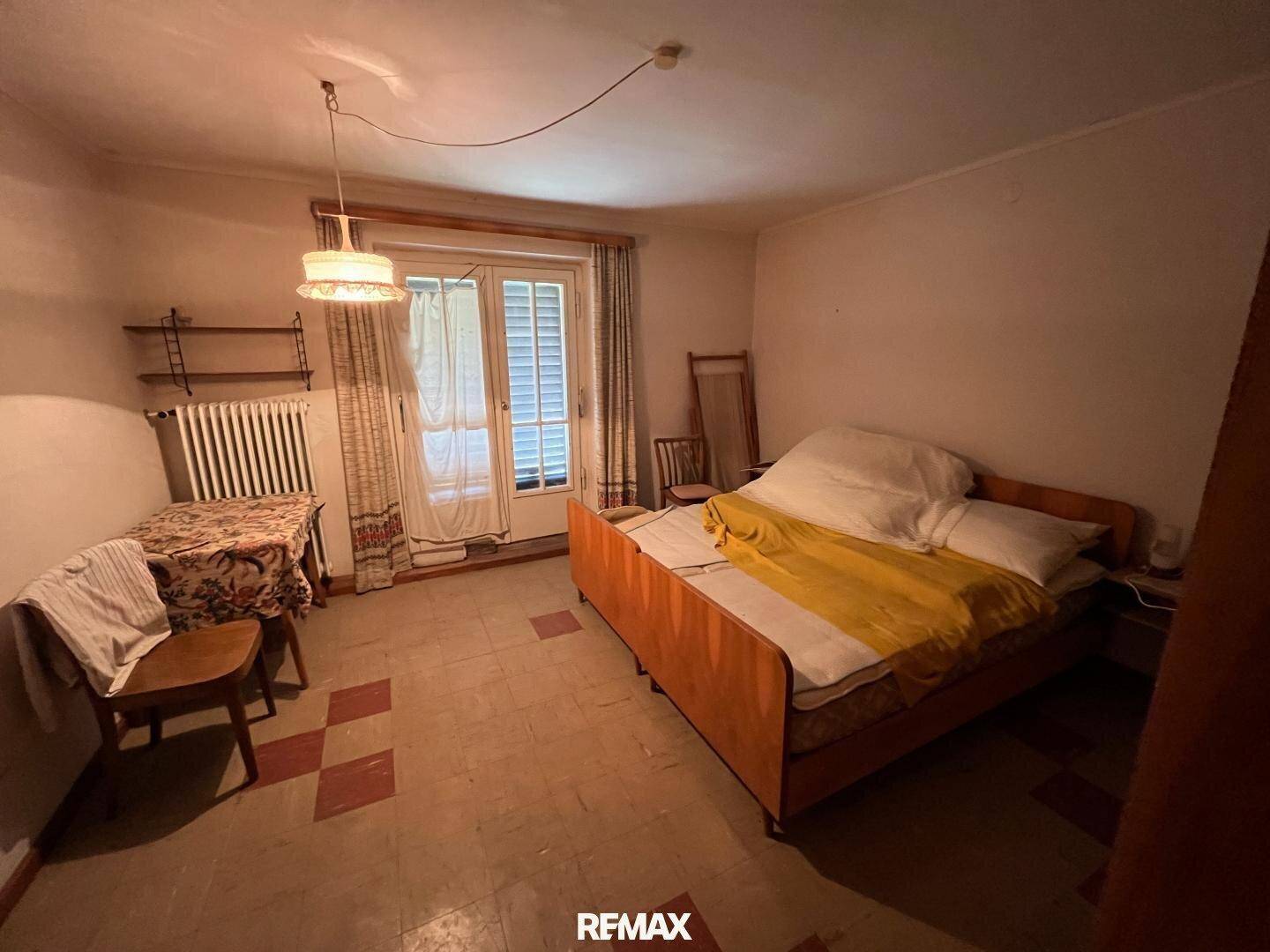 Schlafzimmer mit Bett, Tisch und Zugang zu einem Balkon oder Terrasse.