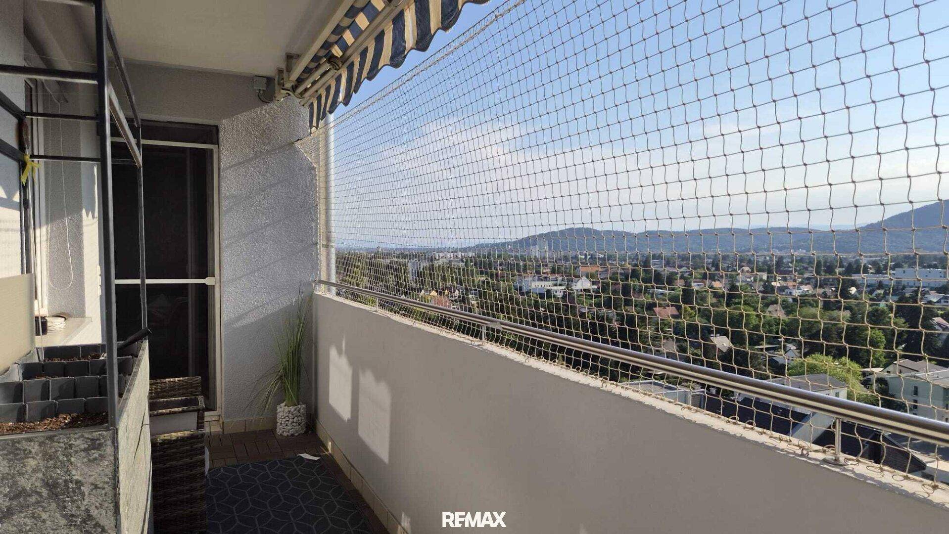 Geräumiger Balkon mit Panoramablick auf die umliegende Landschaft und die Stadt bei Sonnenschein.