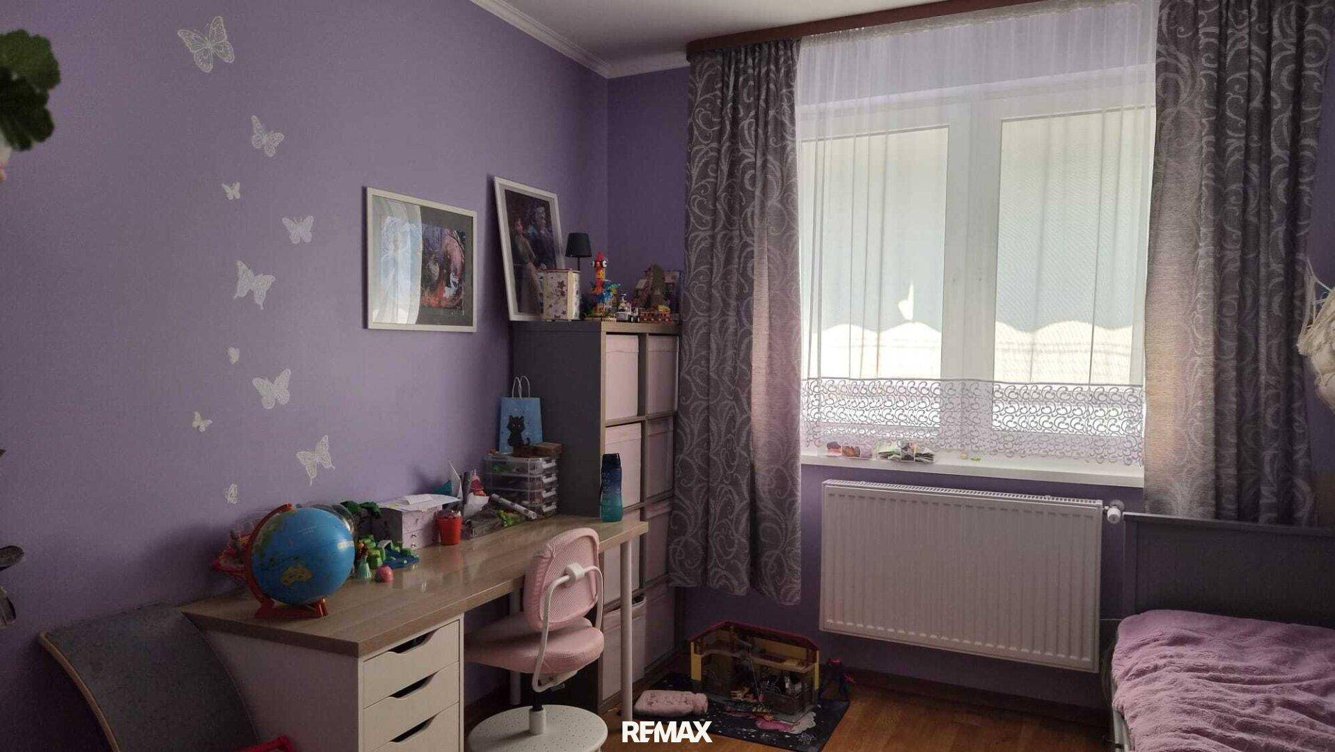 Farbenfrohes Kinderzimmer mit lila Wänden, Schreibtisch und Fenster mit Heizkörper für angenehme Wärme.