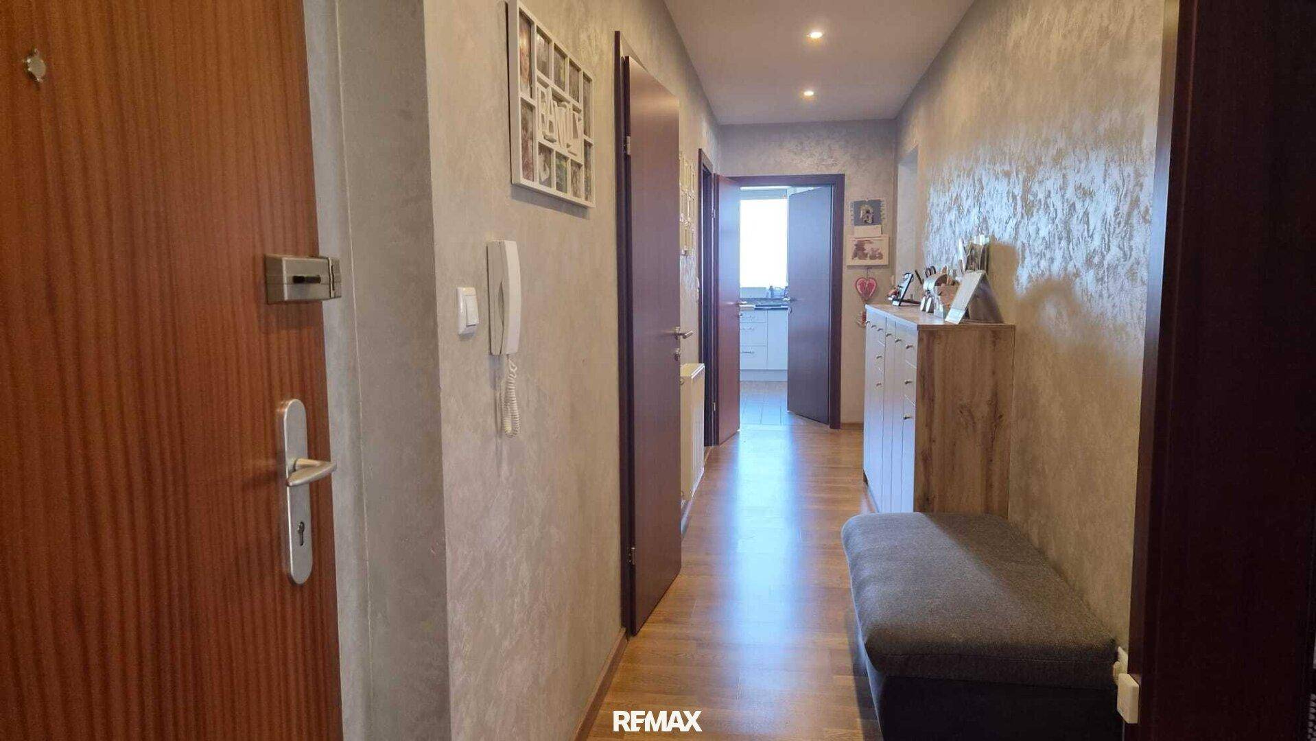 Heller Flur mit Holztüren und strukturierten Wänden, der zu weiteren Räumen der Wohnung führt.