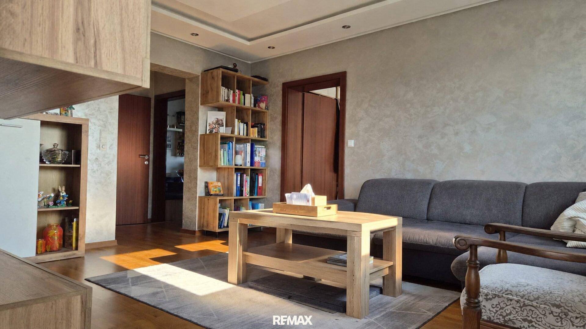 Helles Wohnzimmer mit Holzboden, Bücherregal und bequemer Sitzgelegenheit für entspannte Stunden.