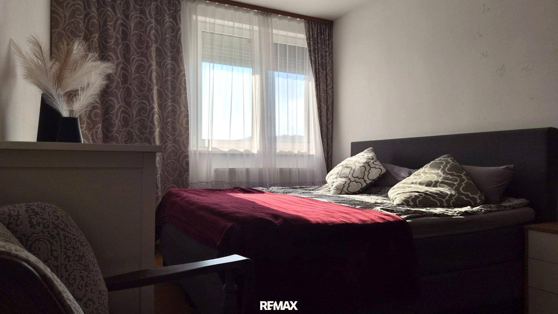 Gemütliches Schlafzimmer mit Doppelbett und großem Fenster, das viel Tageslicht hereinlässt.