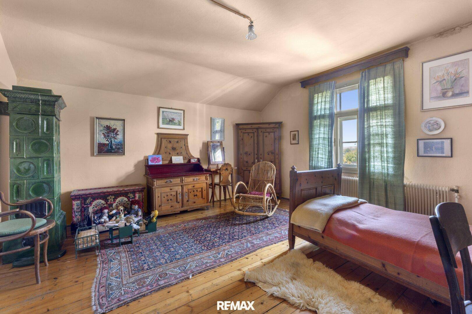 Rustikales Schlafzimmer mit Holzboden, grünem Kachelofen und traditionellen Holzmöbeln für eine gemütliche Stimmung.