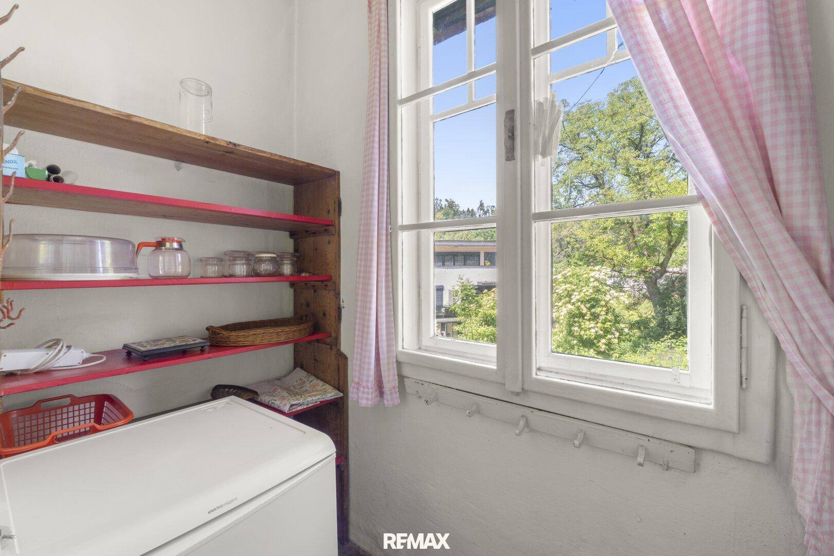 Kleiner Abstellraum mit Regal und Fenster, ideal für Vorräte oder Haushaltsgeräte.
