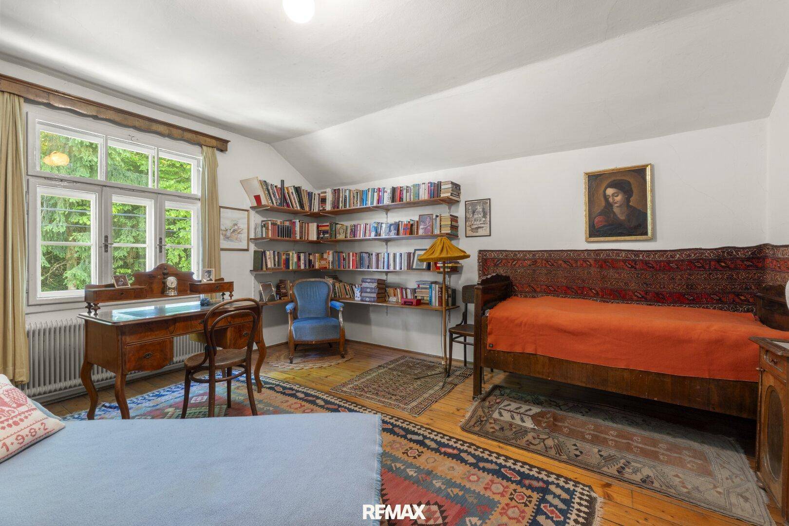 Gemütliches Schlafzimmer mit Holzboden, Bücherregal und traditionellem Schreibtisch in warmer Atmosphäre.