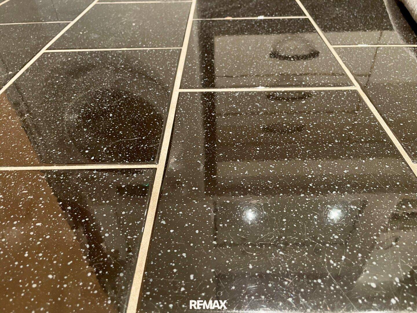 Nahaufnahme des schwarzen Fliesenbodens mit weißen Sprenkeln.