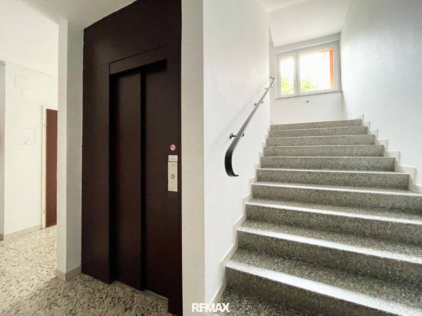 Treppenhaus mit Granitstufen und einem Aufzug im Mehrfamilienhaus.