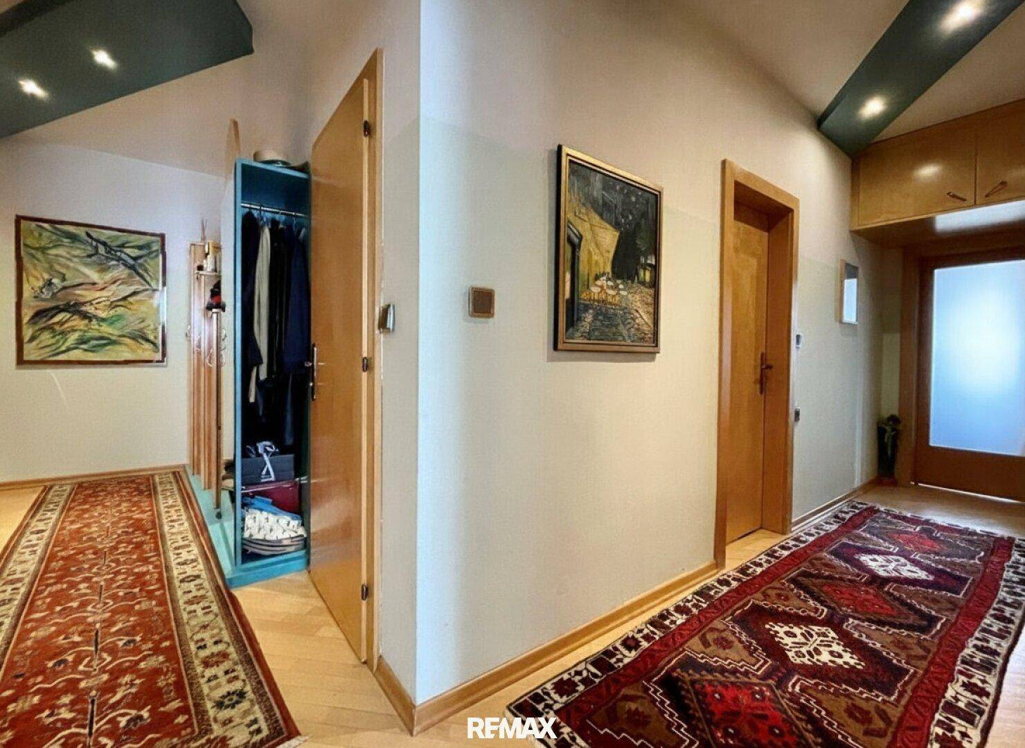 Langer Flur mit Holzboden, Teppich und einem offenen Kleiderschrank.