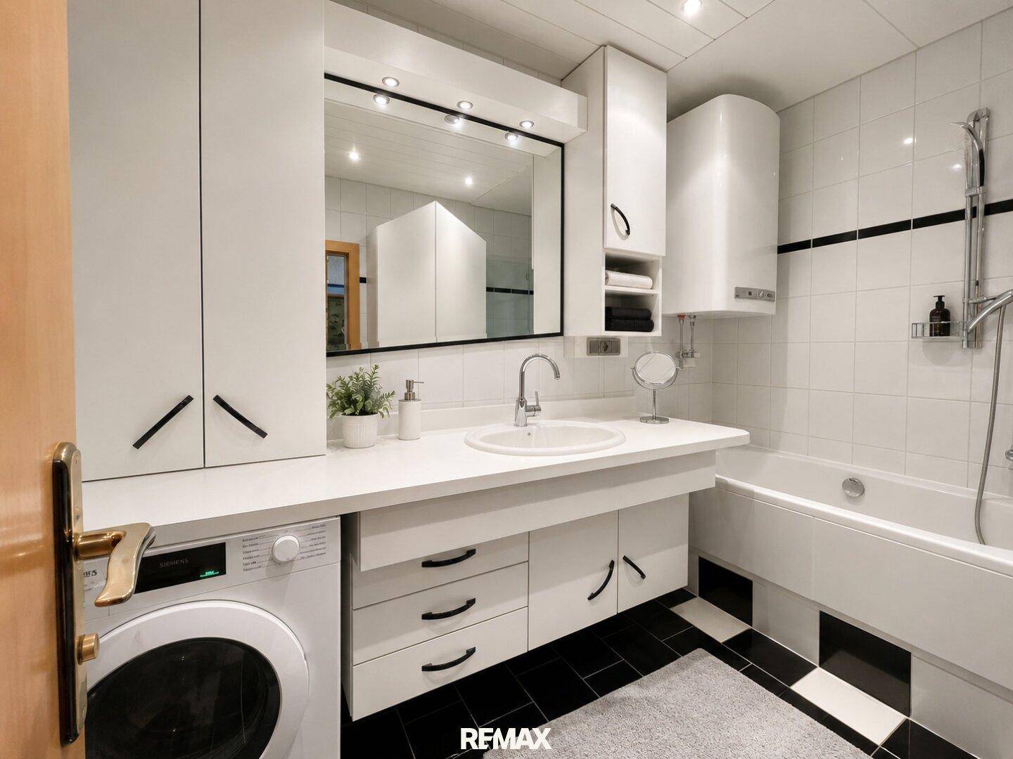 Modernes Badezimmer mit Badewanne, Waschmaschine und großem Spiegel.