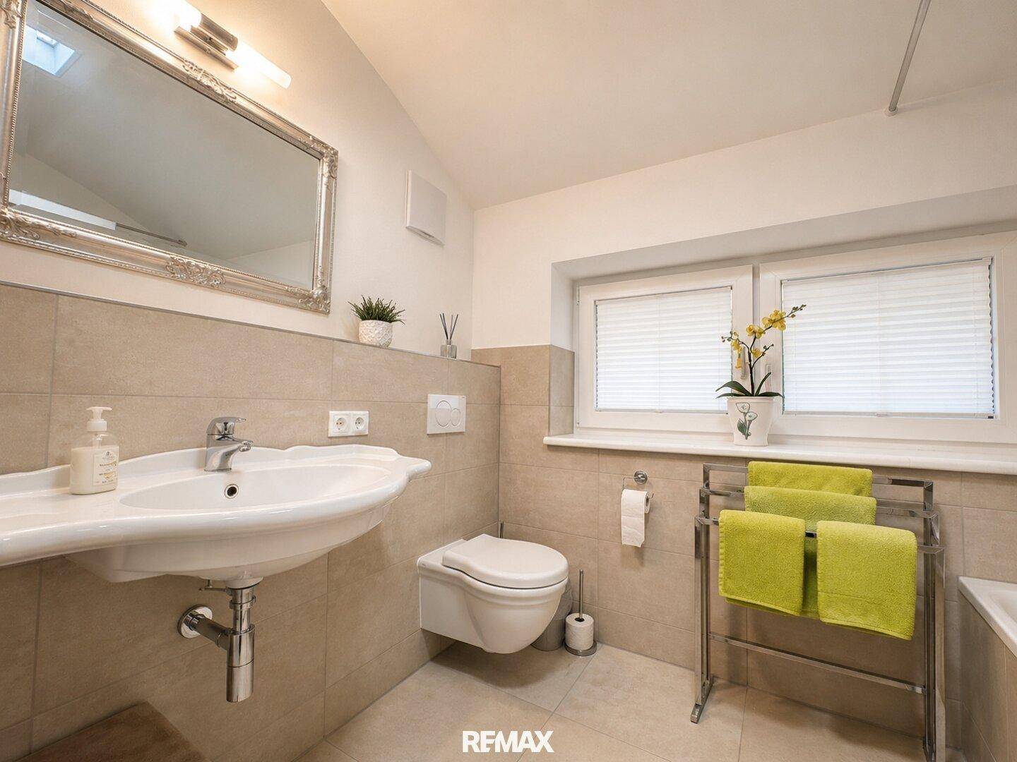 Modernes Badezimmer mit Waschtisch, wandhängendem WC, Fenster und beigen Fliesen.