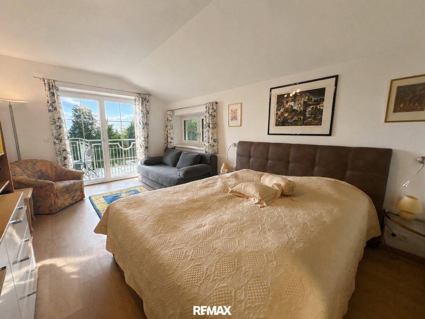Schlafzimmer mit Doppelbett, Sofa und Zugang zu einem Balkon mit weitem Blick in die Landschaft.