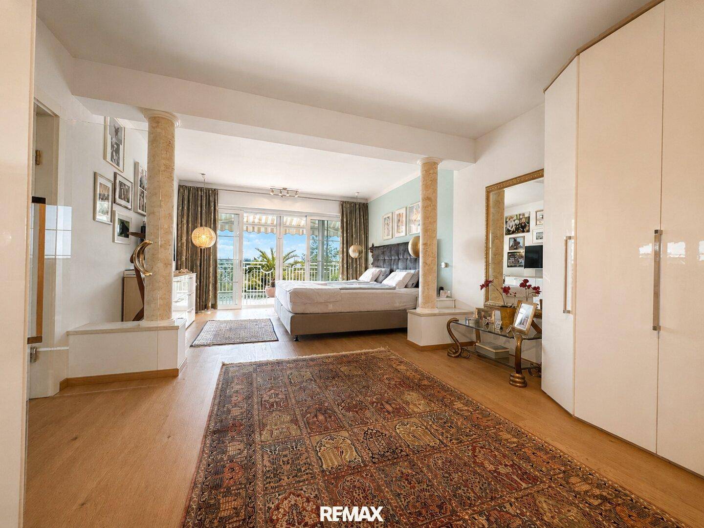 Großzügiges Schlafzimmer mit Säulen, Doppelbett und Zugang zu einem Balkon mit Panoramablick.