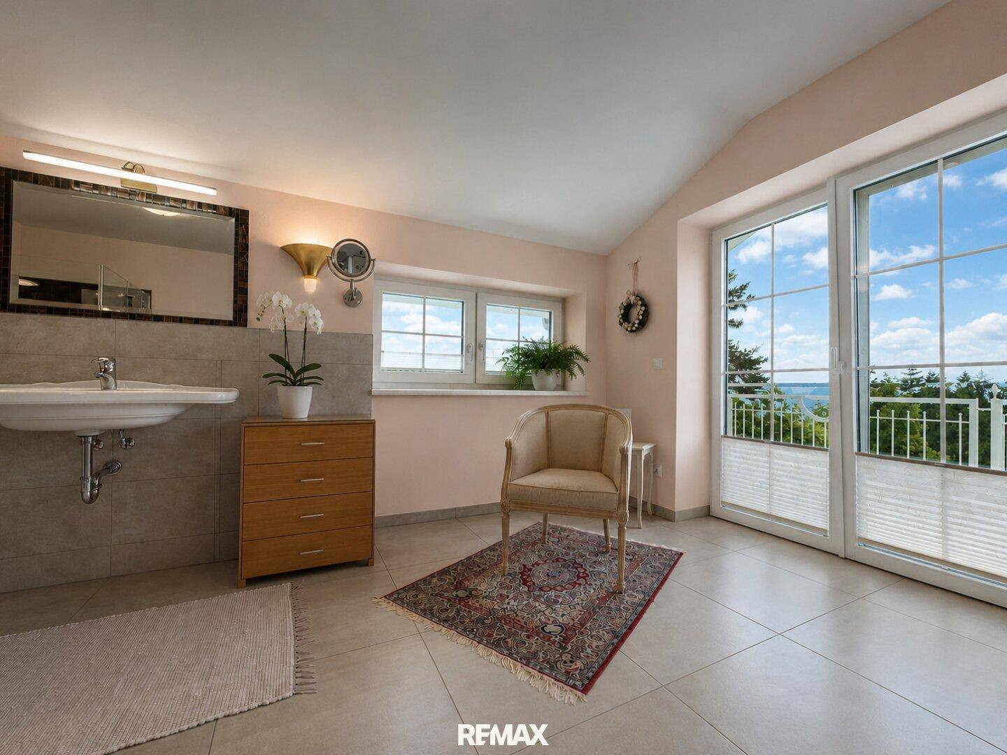 Geräumiges Badezimmer mit Waschtisch, Fenster und Zugang zu einem französischen Balkon mit Aussicht.