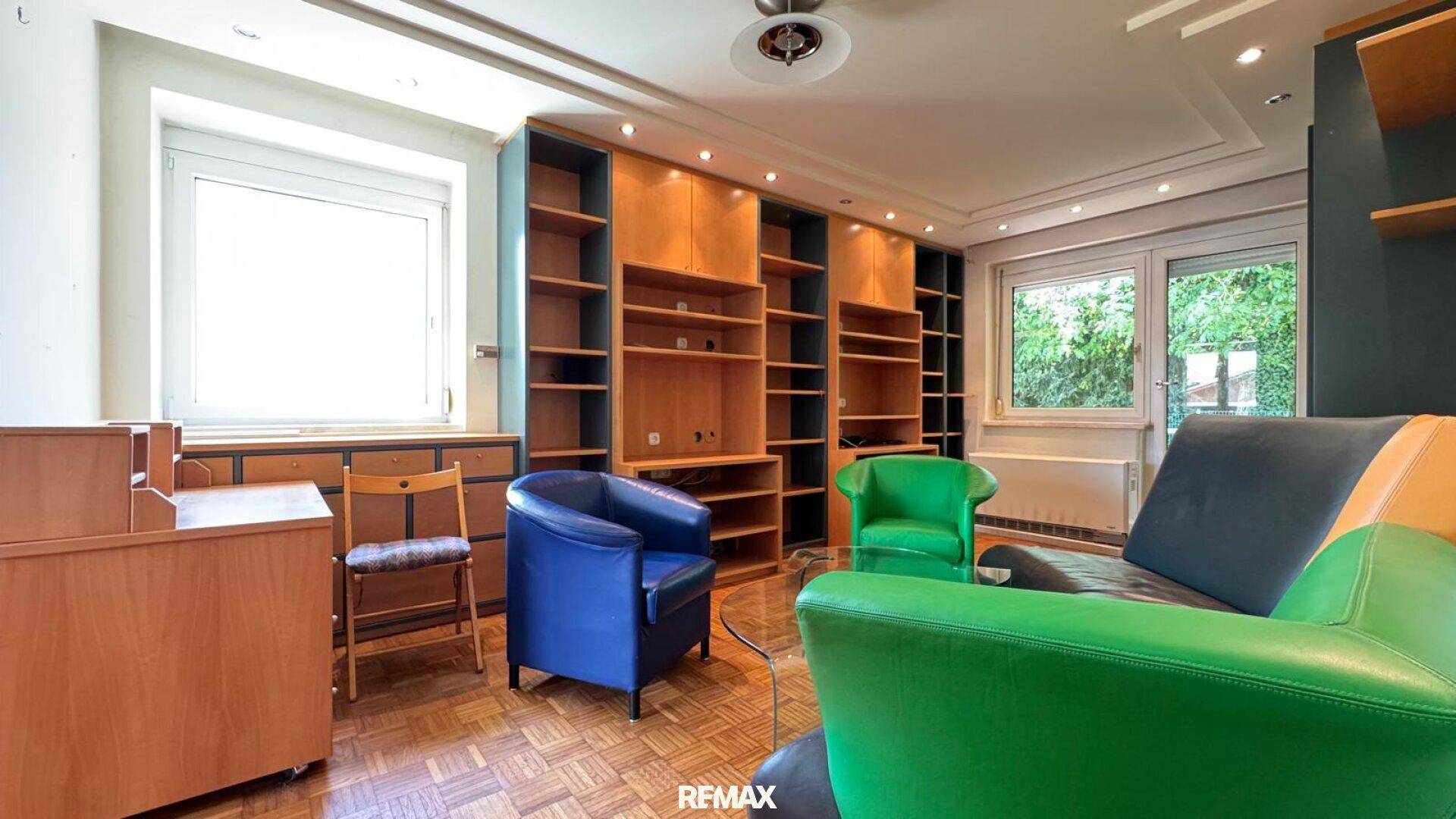 Helles Wohnzimmer mit Parkettboden, Einbauregalen und Zugang zu einem Außenbereich.