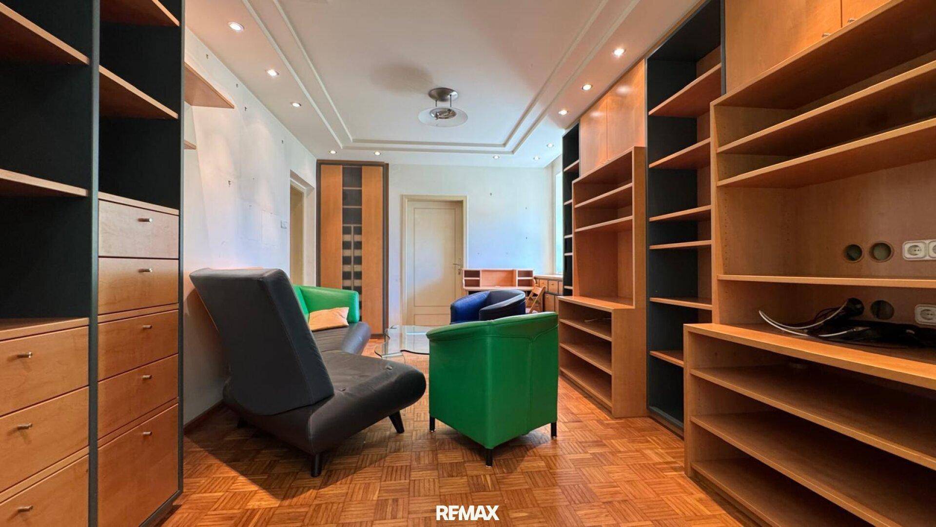 Geräumiges Wohnzimmer mit umfangreichen Holzregalen, Parkettboden und bunten Akzenten.