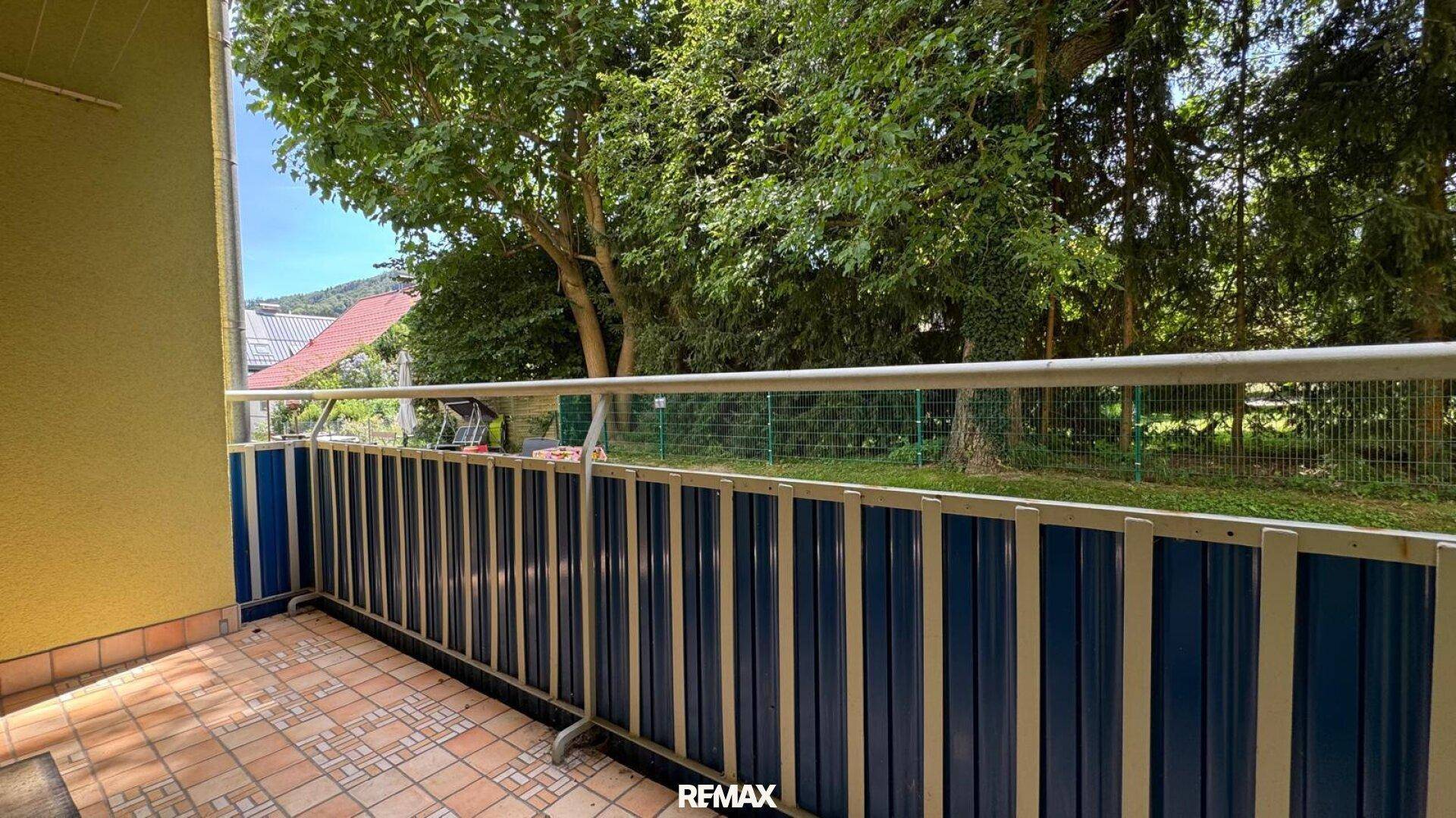 Balkon mit Fliesenboden und Blick auf die grüne Umgebung, ideal zum Entspannen.