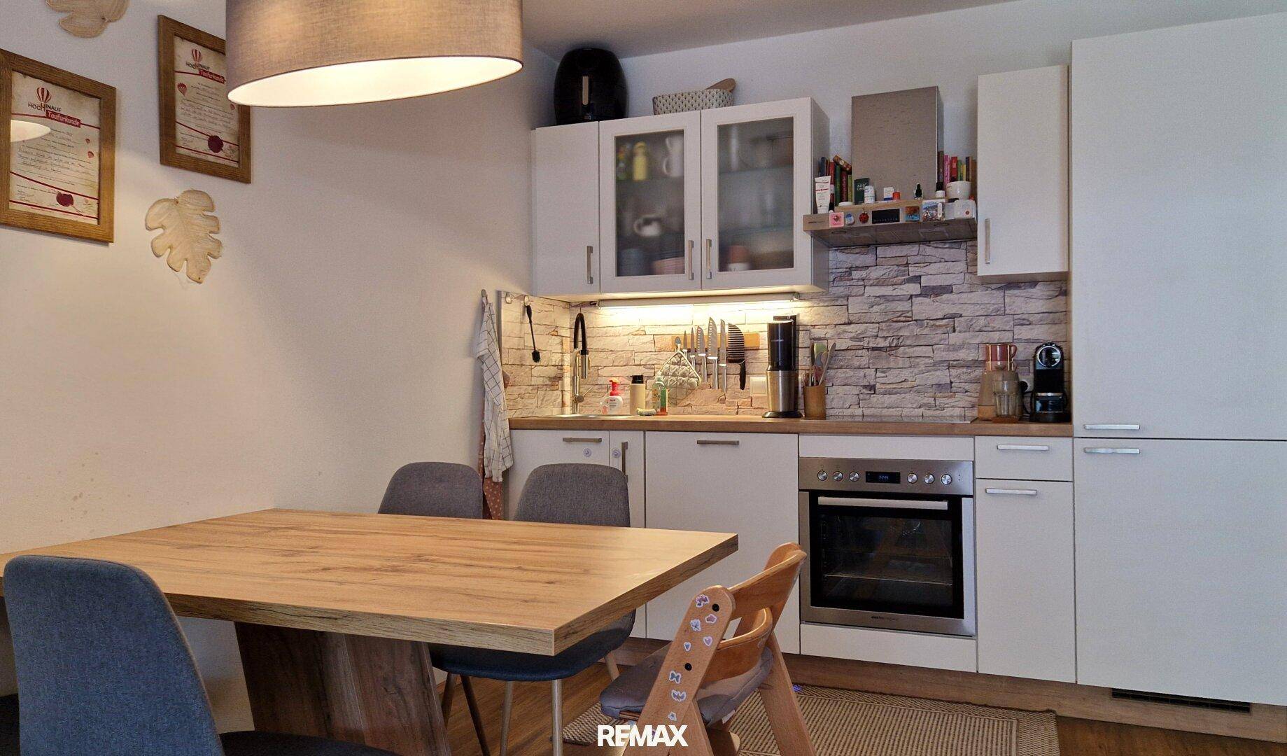 Moderne Einbauküche mit Essbereich und Steinwand-Akzent.