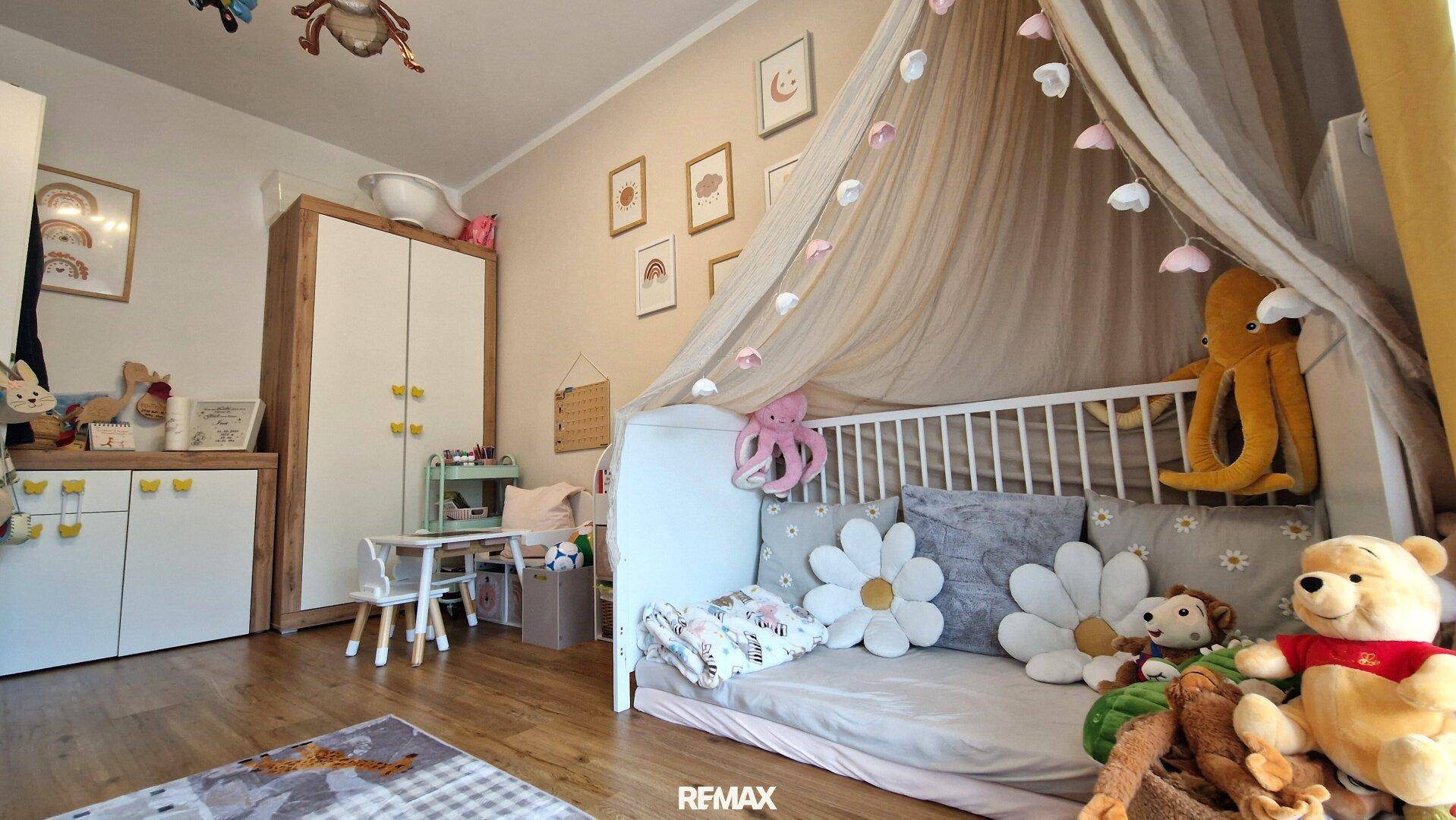 Charmantes Kinderzimmer mit Holzboden, Spielzeug und einem Himmelbett.