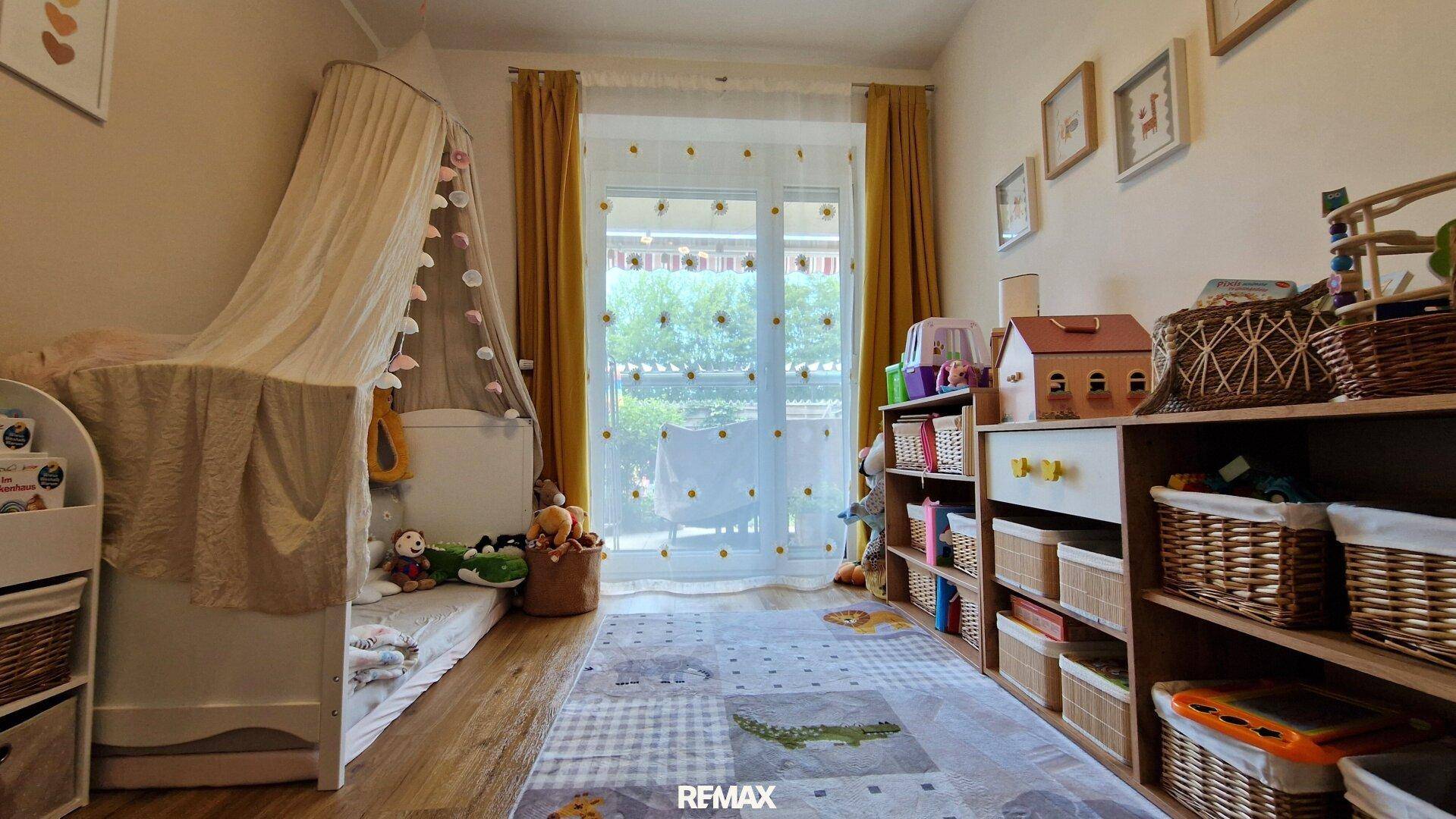 Freundliches Kinderzimmer mit viel Stauraum für Spielzeug und Zugang zum Außenbereich.