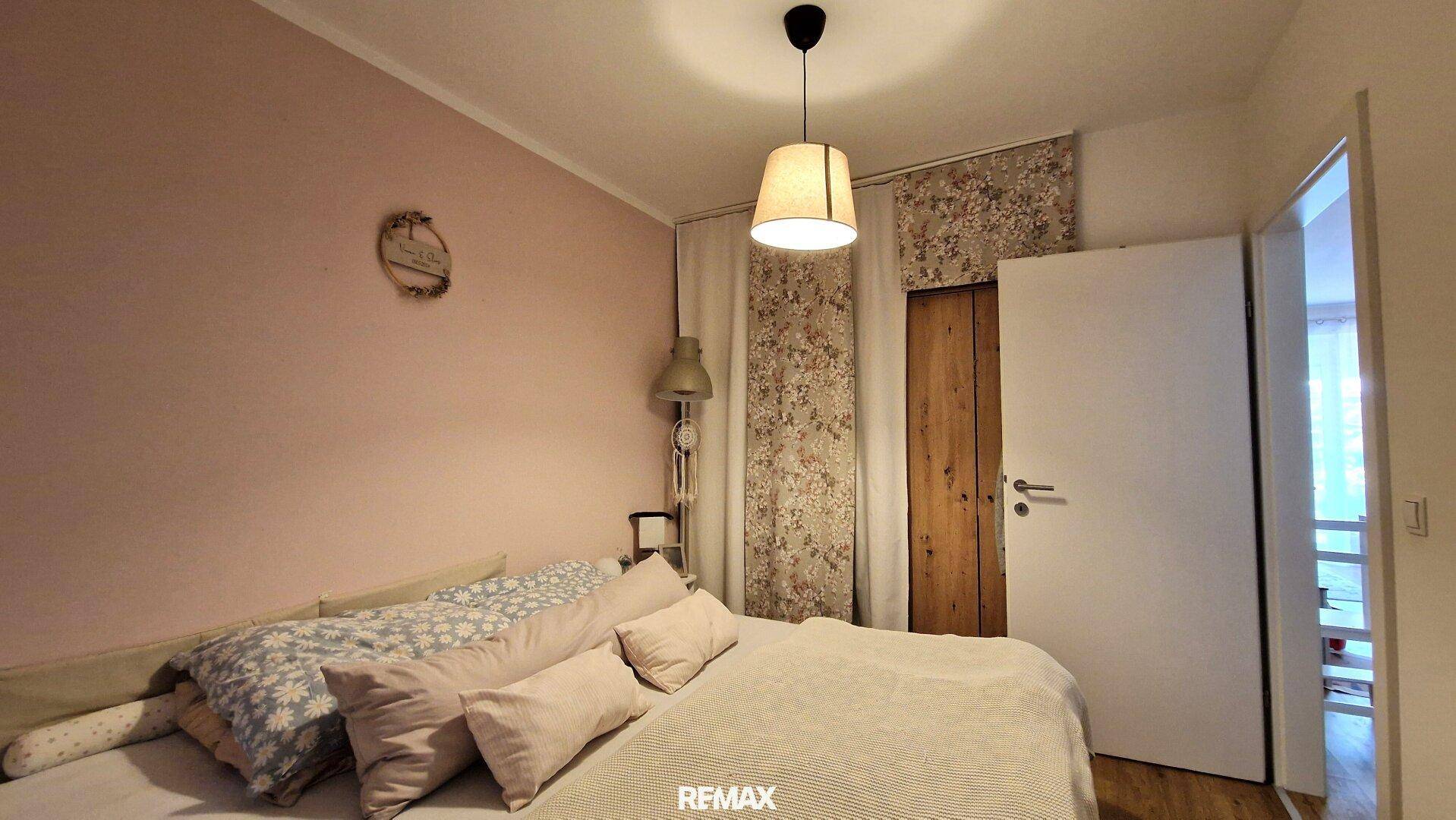Gemütliches Schlafzimmer mit rosa Wänden und Holztür.