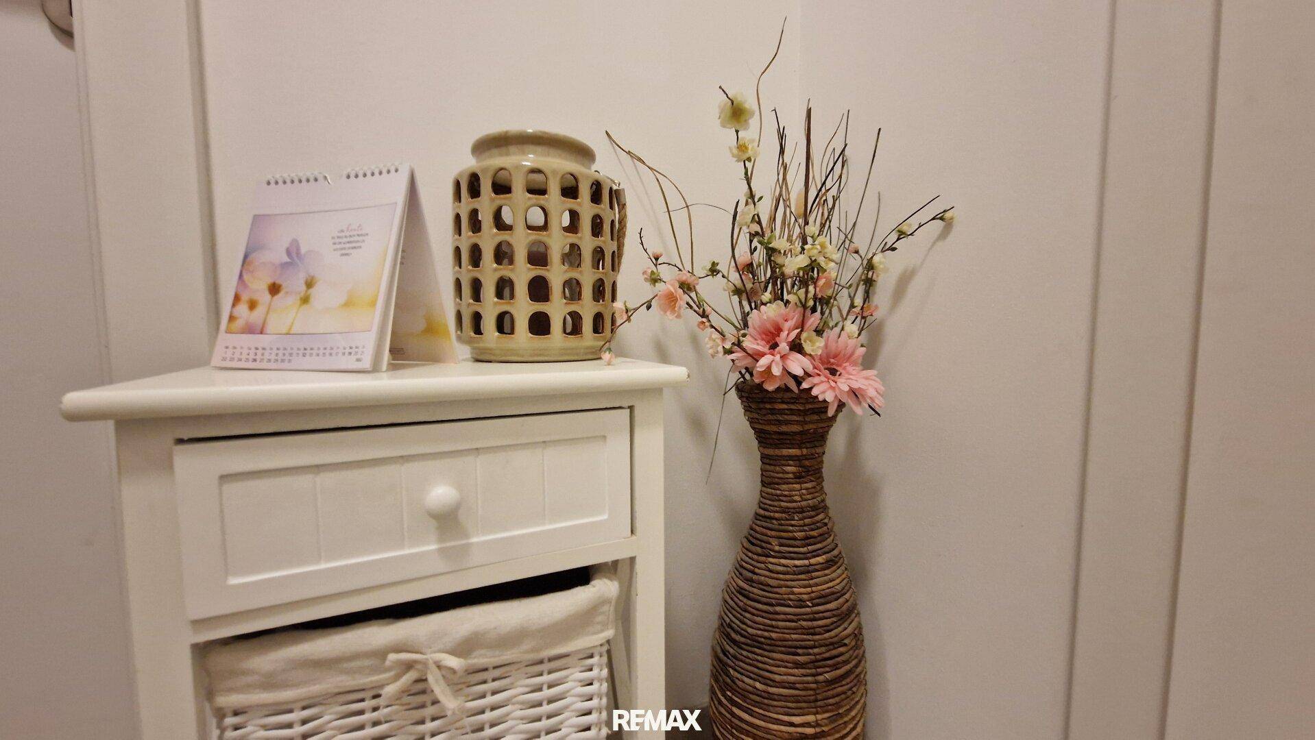 Dekorative Ecke im Flur mit Blumen und einem kleinen Beistelltisch.