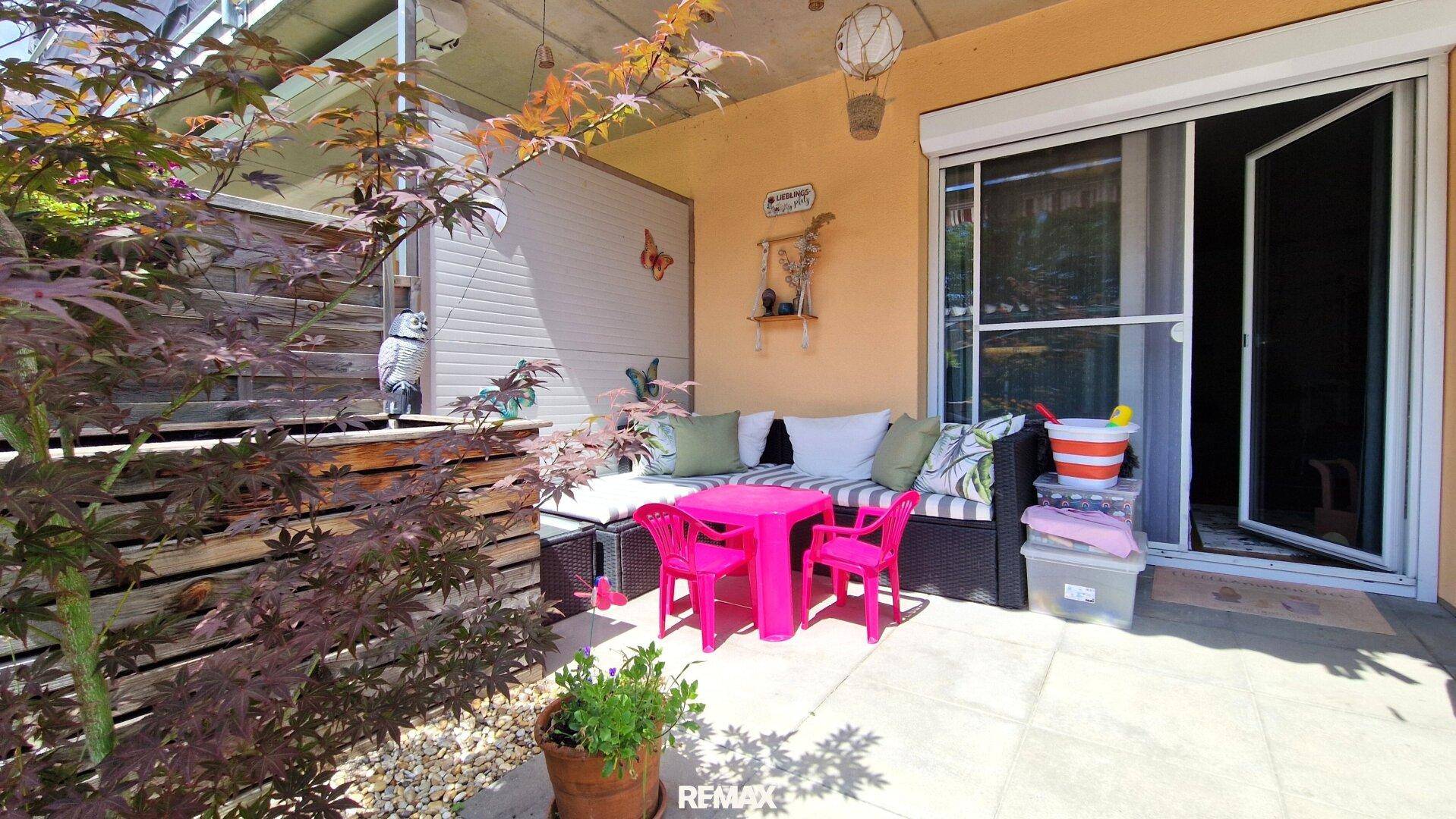 Überdachte Terrasse mit Sitzgelegenheiten und Pflanzen, ideal zum Entspannen.
