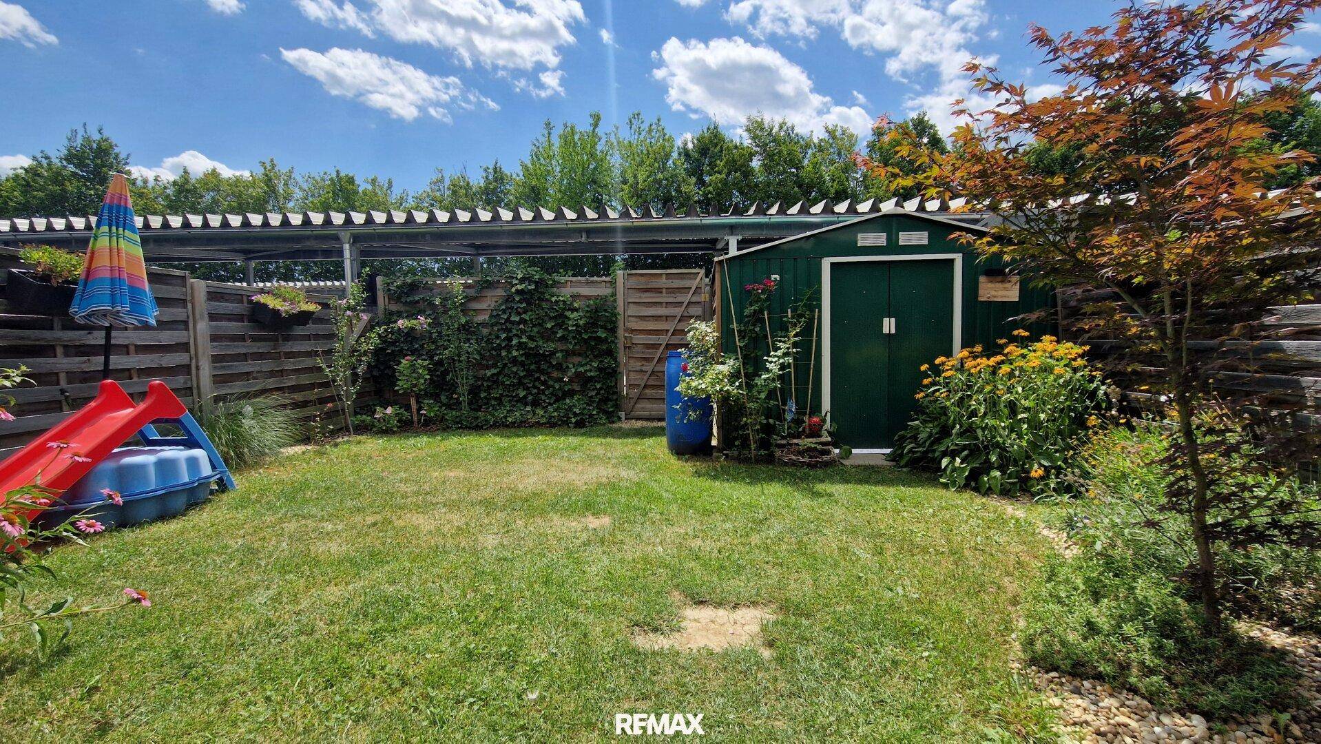 Gepflegter Garten mit Rasenfläche, Gartenhaus und Spielgeräten.