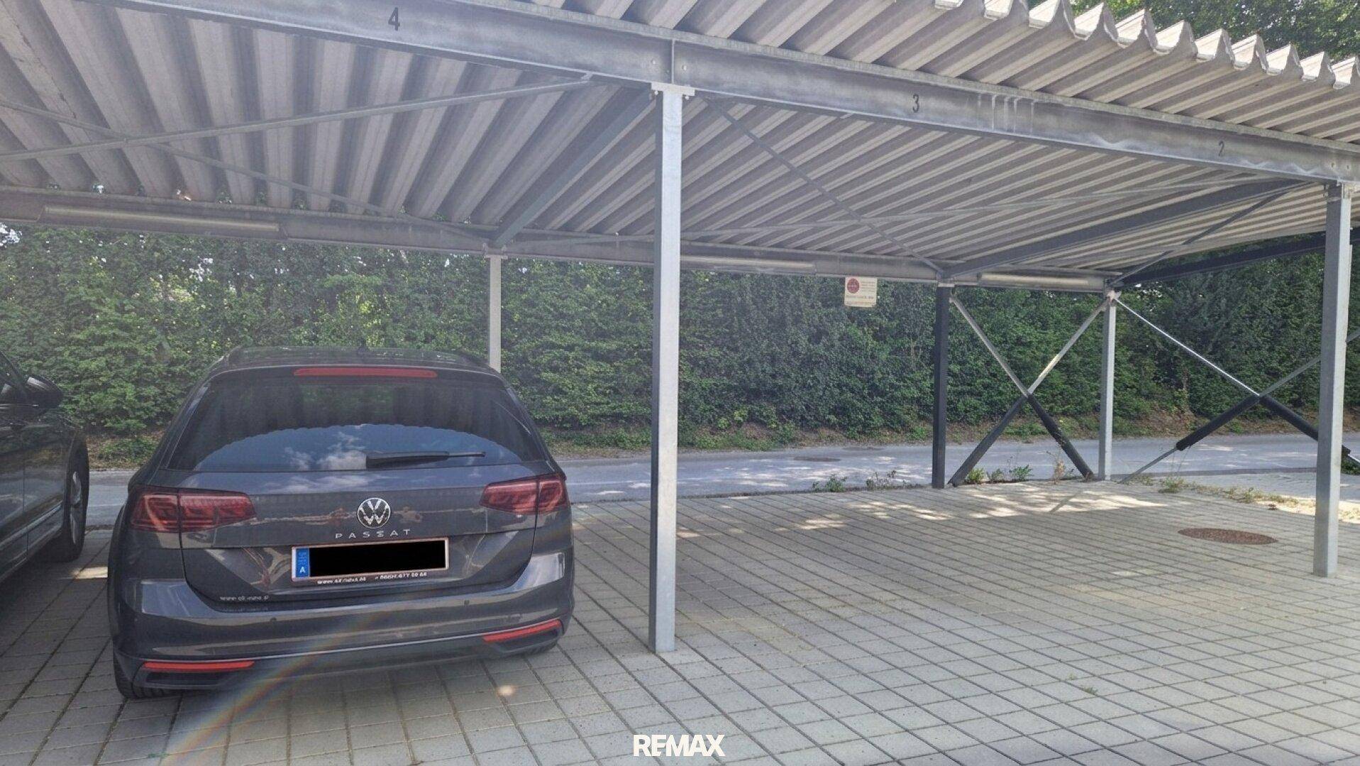 Überdachter Parkplatz mit einem geparkten Auto.