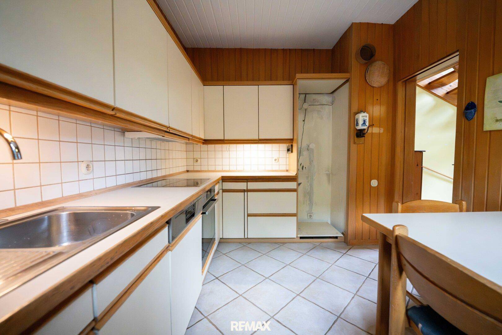 Gemütliche Küche mit weißen Schränken, Holzvertäfelung und Essbereich.