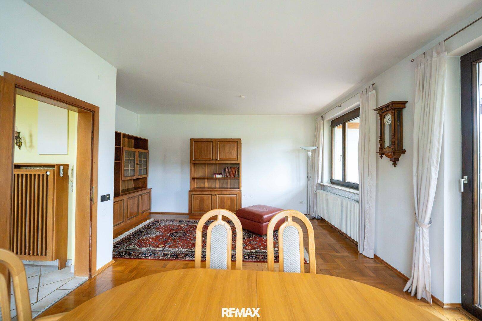 Heller Wohn- und Essbereich mit Parkettboden, Holzmöbeln und Zugang zum Balkon.