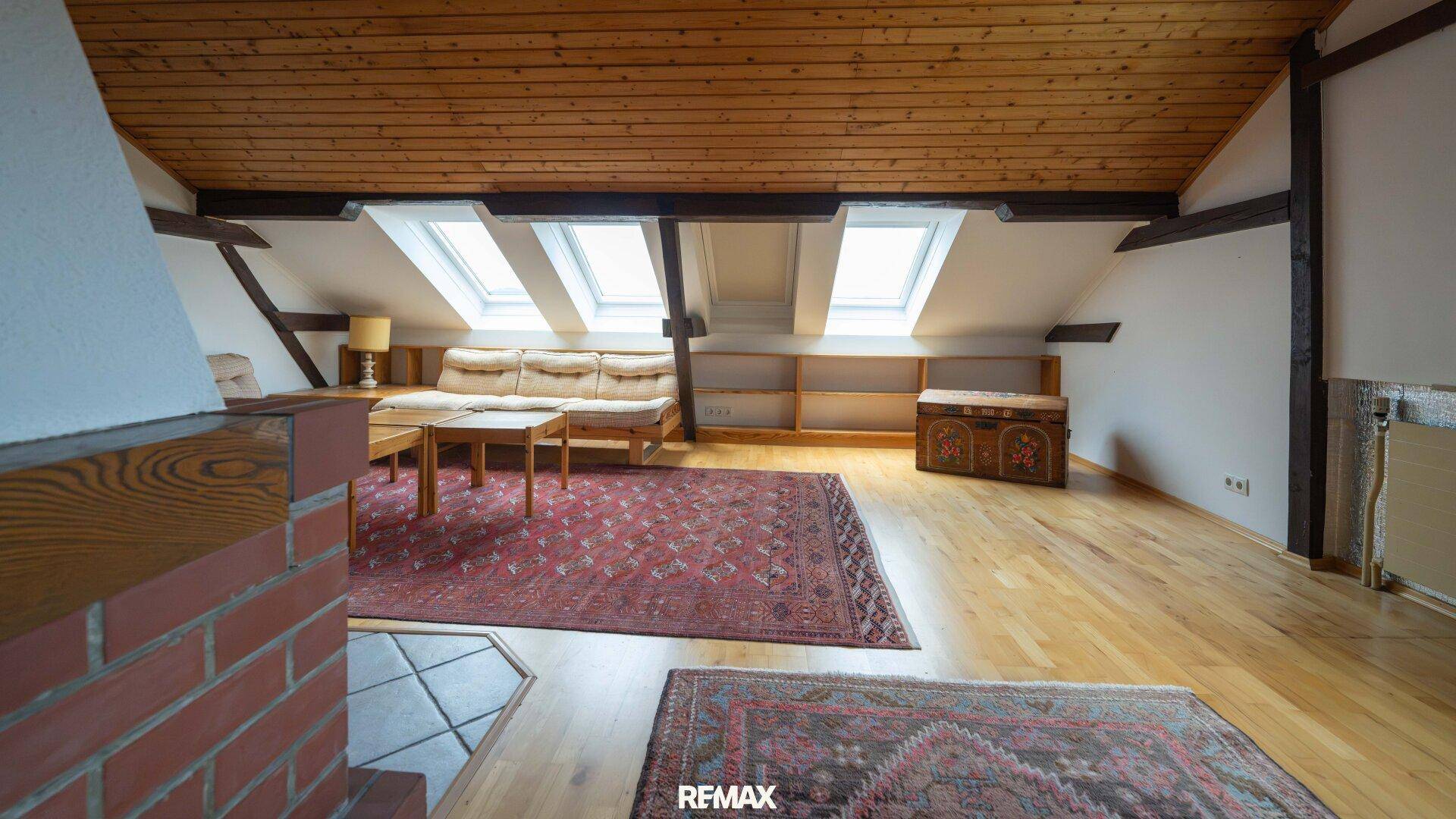 Dachgeschoss-Wohnzimmer mit Holzbalken, Dachfenstern und rustikalem Charme.