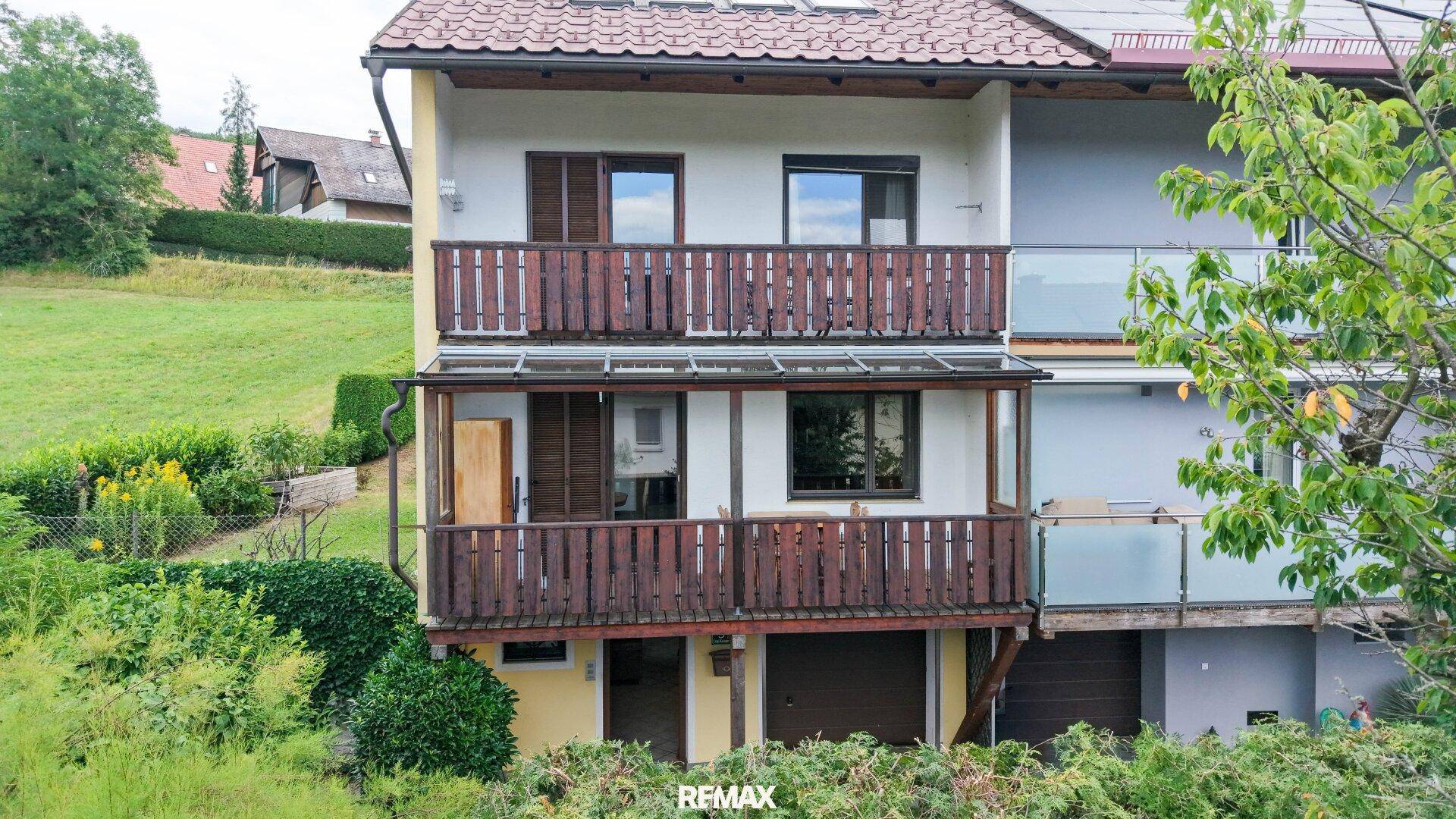 Rückansicht eines Wohnhauses mit mehreren Balkonen und Blick ins Grüne.