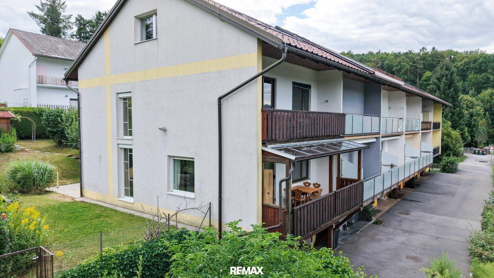Rückansicht des Reihenhauses mit mehreren Balkonen und angrenzendem Parkplatz.